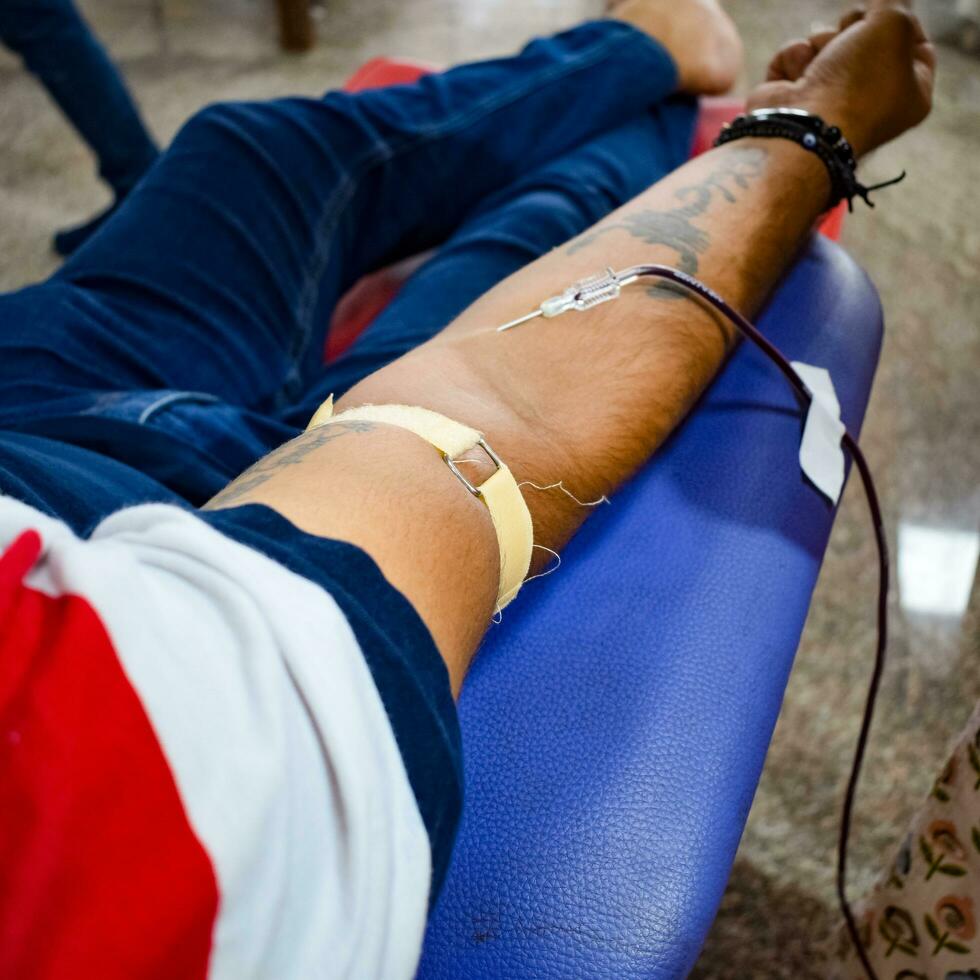 Blood donor at Blood donation camp held with a bouncy ball holding in hand at Balaji Temple, Vivek Vihar, Delhi, India, Image for World blood donor day on June 14 every year, Blood Donation Camp photo