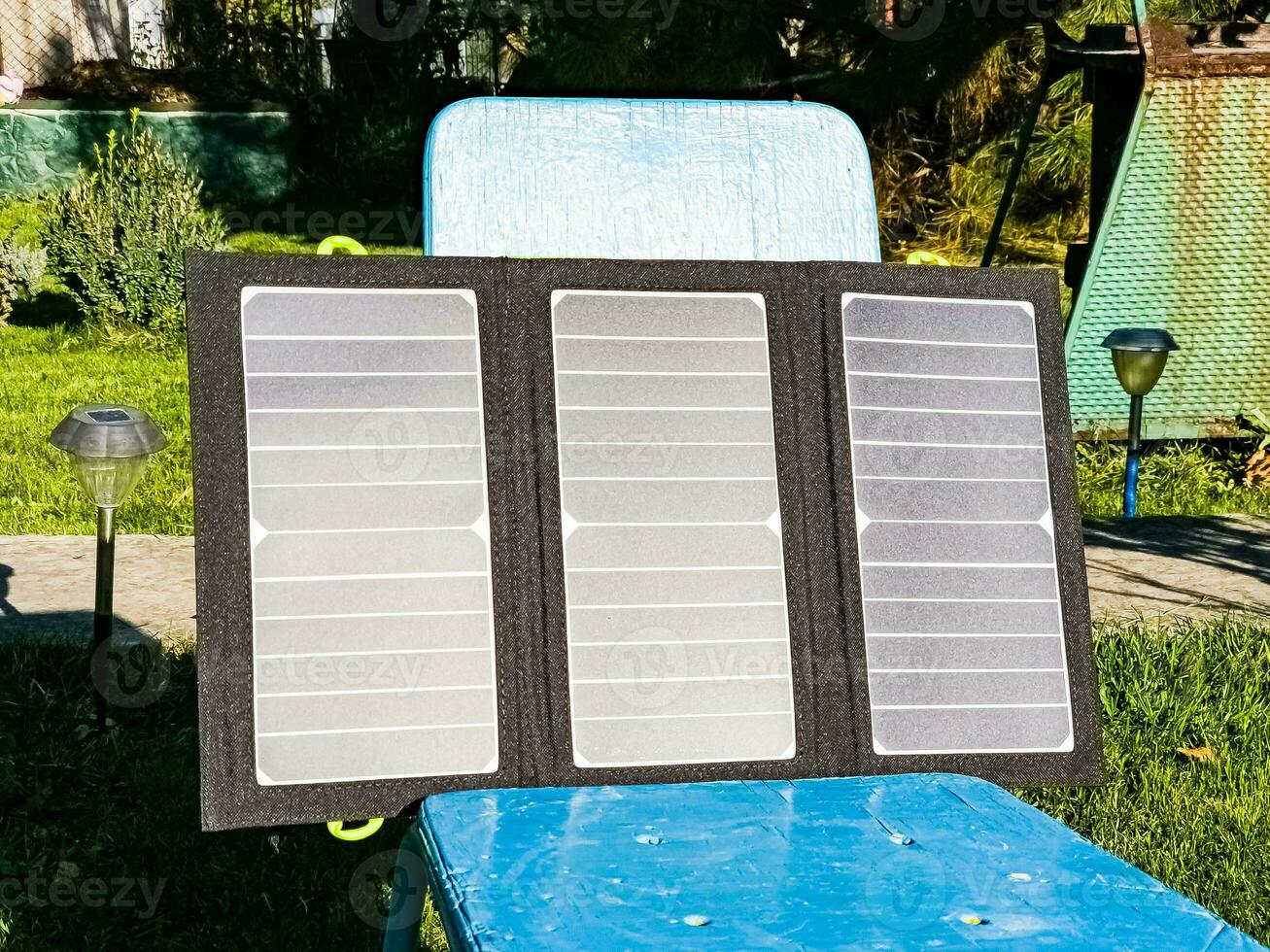 Charging a portable solar battery from the sun at a summer camping site. Clean energy for camp use. photo