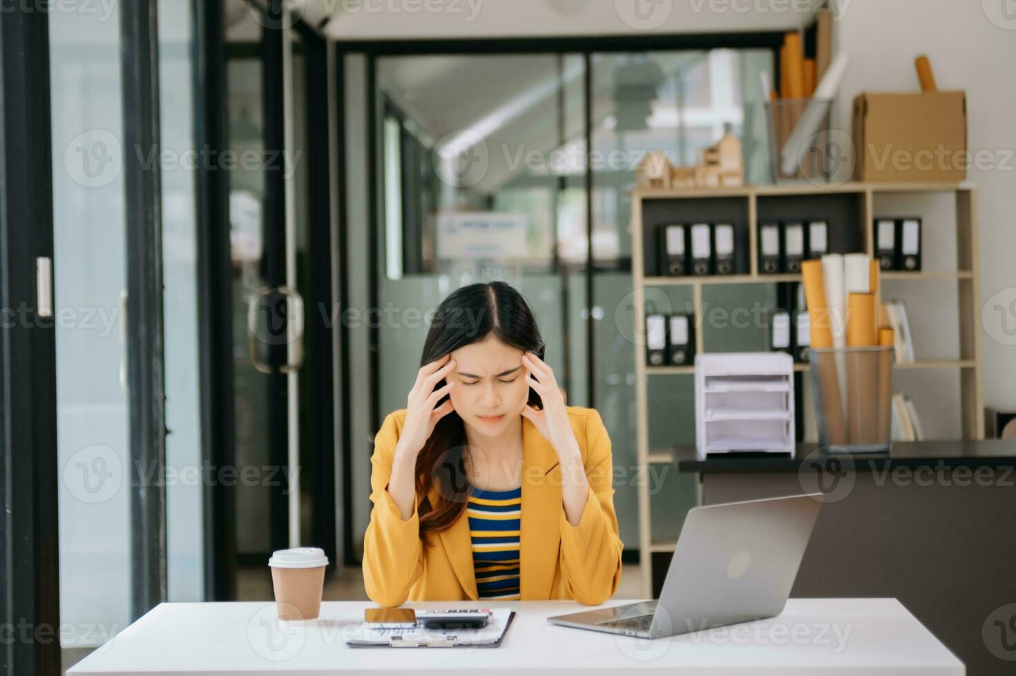 Woman who is tired and overthinking from working with tablet and laptop at modern office. photo