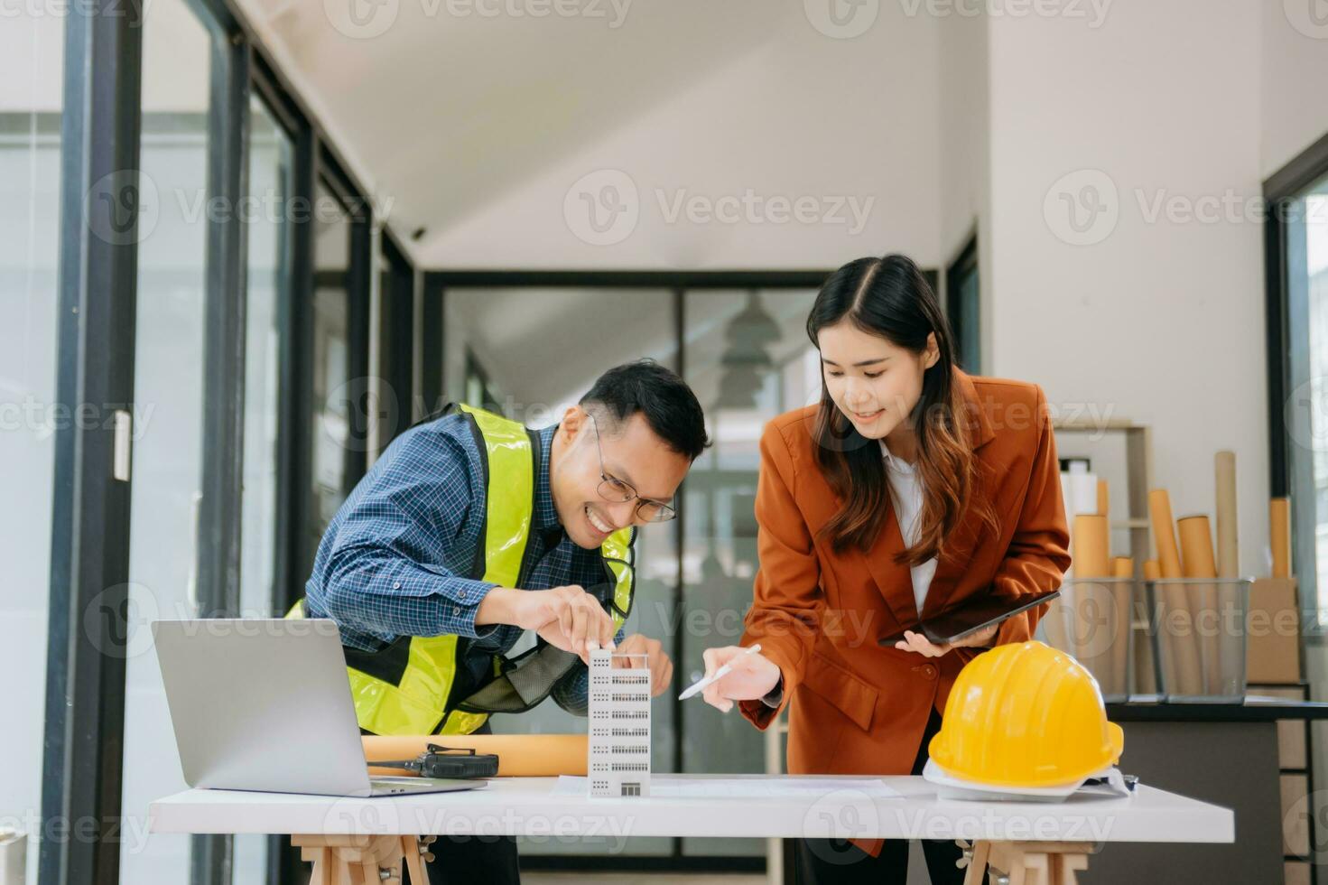 Engineer teams meeting working together wear worker helmets hardhat with on architectural project site and making model house. Asian industry professional team in modern office photo