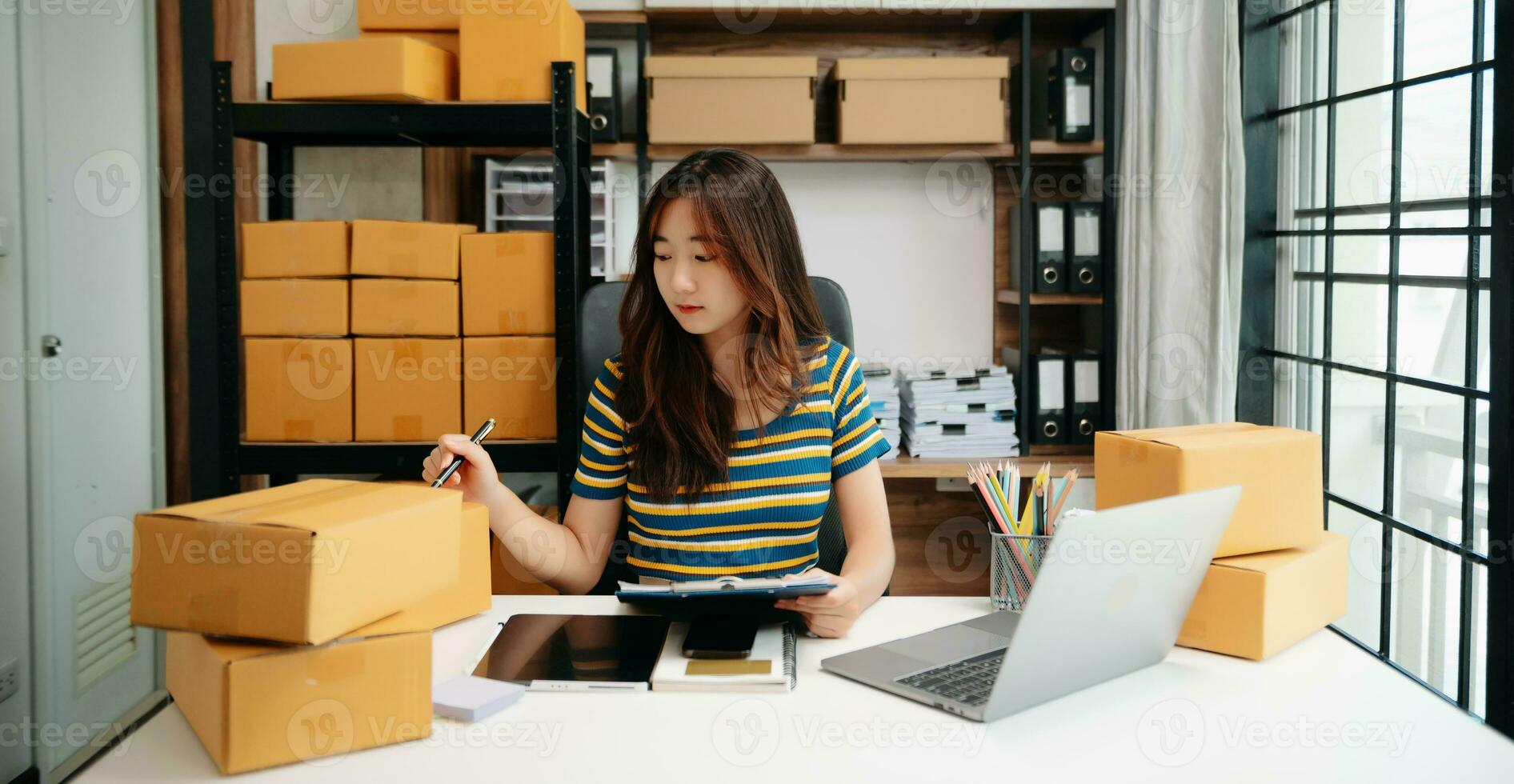Young woman holding a smartphone, tablet showing payment success and credit card with yellow parcel box as online shopping concept photo