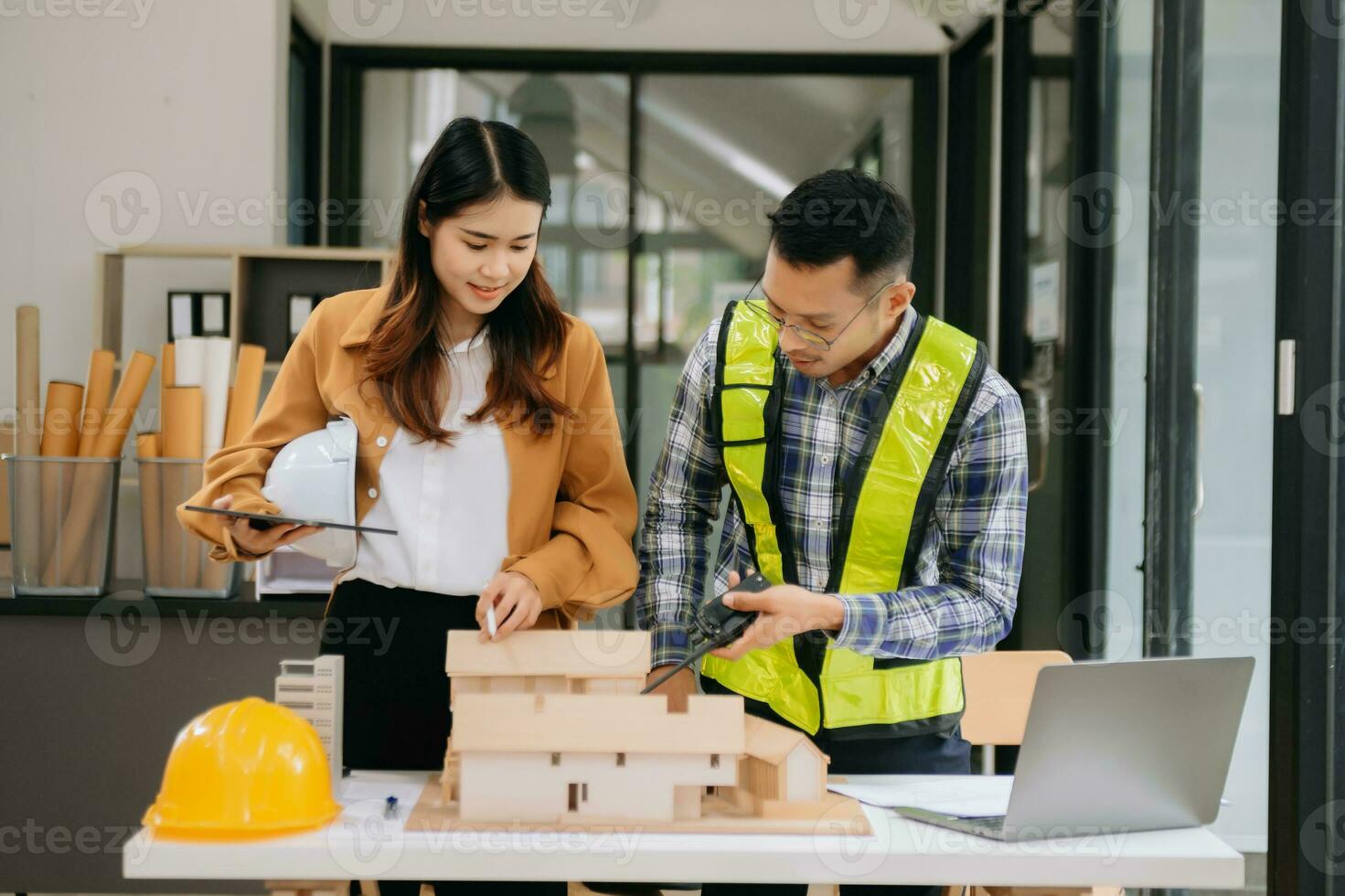 Engineer teams meeting working together wear worker helmets hardhat with on architectural project site and making model house. Asian industry professional team in modern office photo
