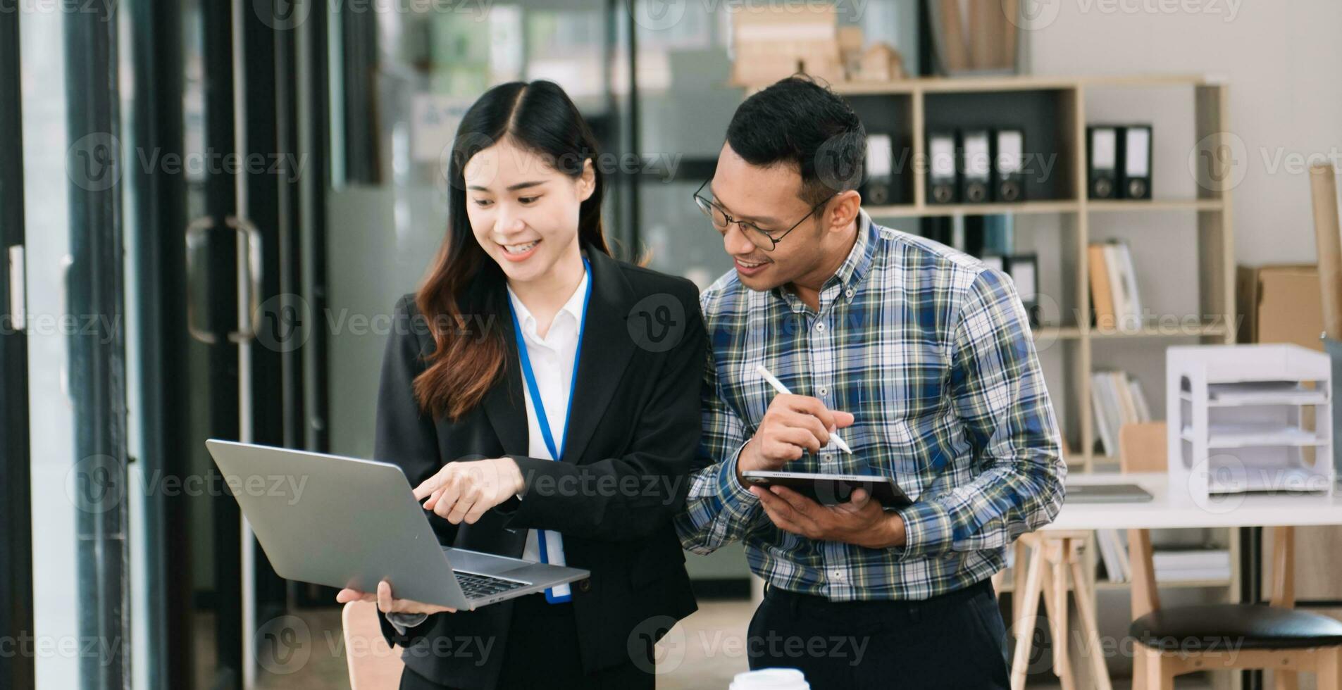 contento gente de negocios mientras colaborando en un nuevo proyecto en un oficina. diverso gente de negocios utilizando un ordenador portátil y tableta foto