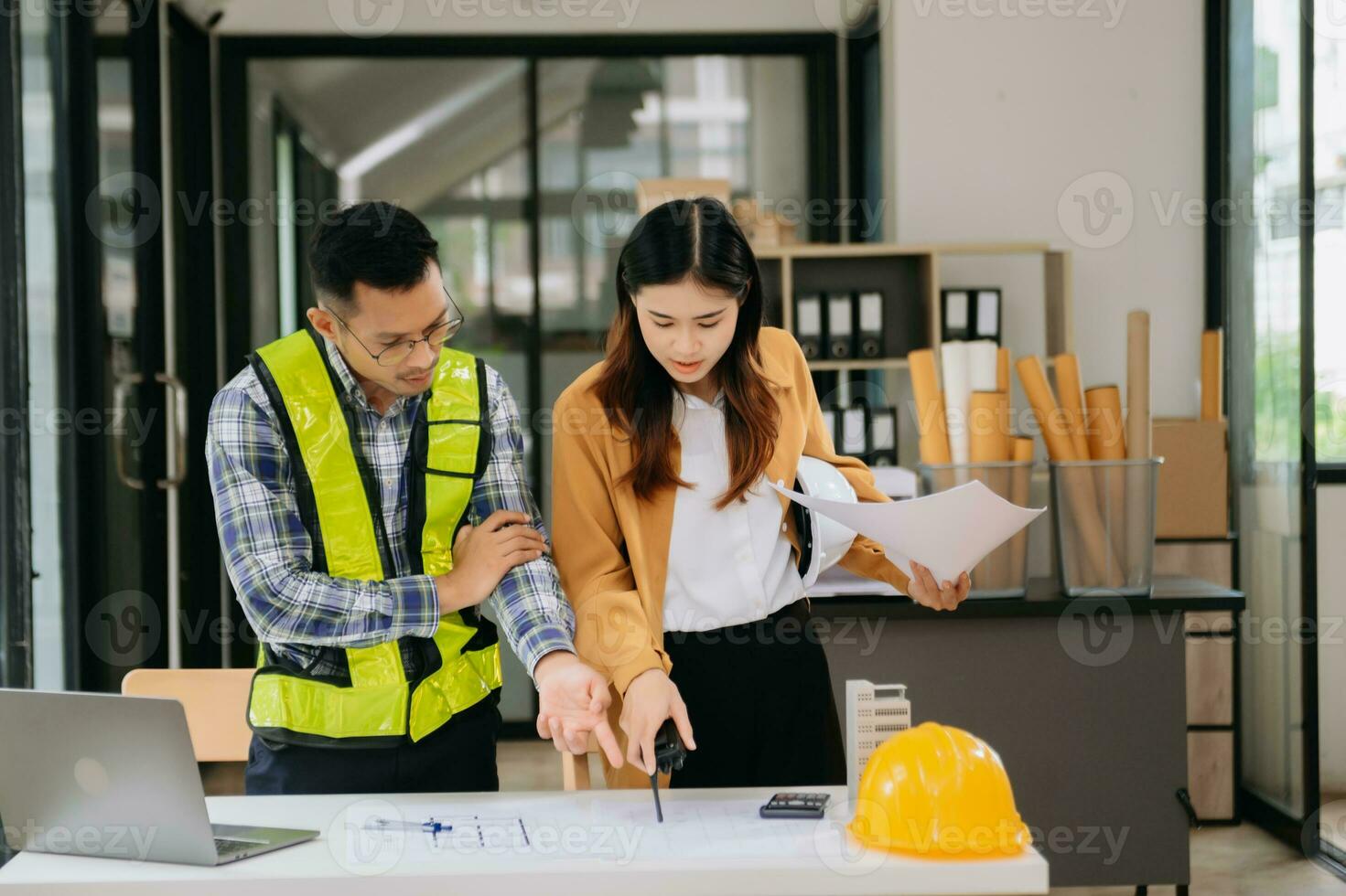 Engineer teams meeting working together wear worker helmets hardhat with on architectural project site and making model house. Asian industry professional team in modern office photo