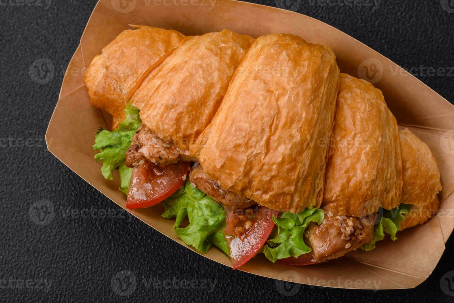 Delicious fresh crispy croissant with chicken or beef meat, lettuce, tomatoes, spices and sauce photo