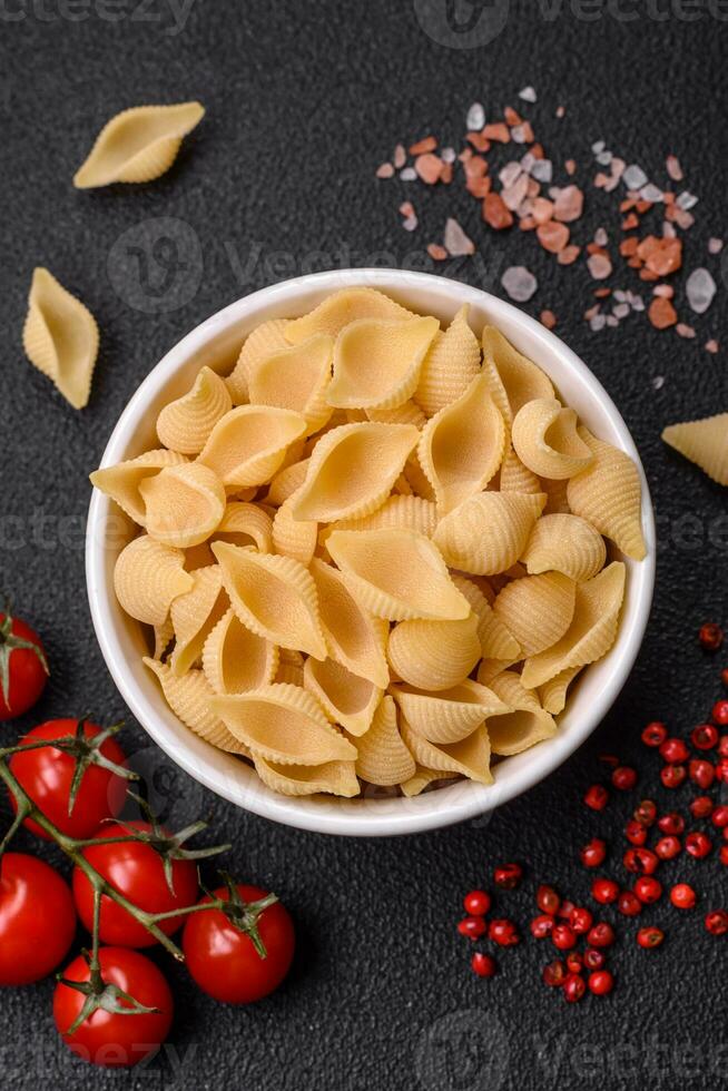 Raw Italian pasta conchiglie from durum wheat with vegetables, salt and spices photo