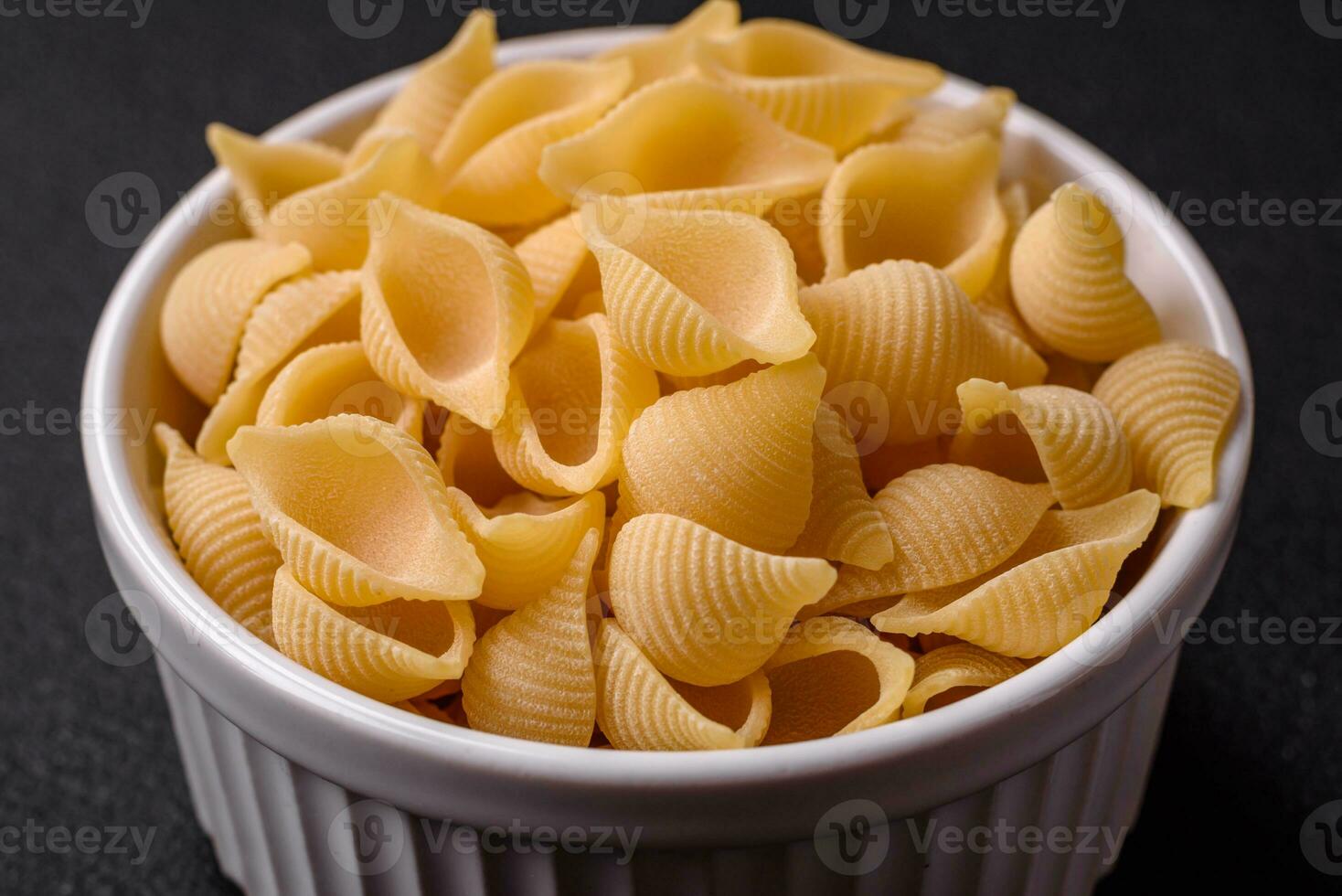 Raw Italian pasta conchiglie from durum wheat with vegetables, salt and spices photo