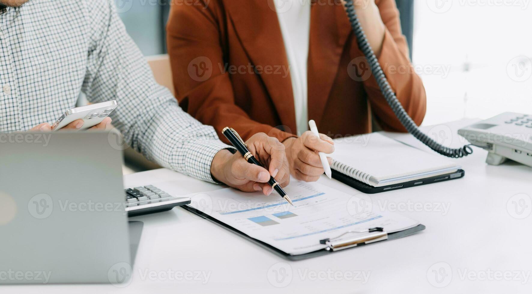 Businessman hand using laptop and tablet with social network diagram and two colleagues discussing data on desk as concept in office photo