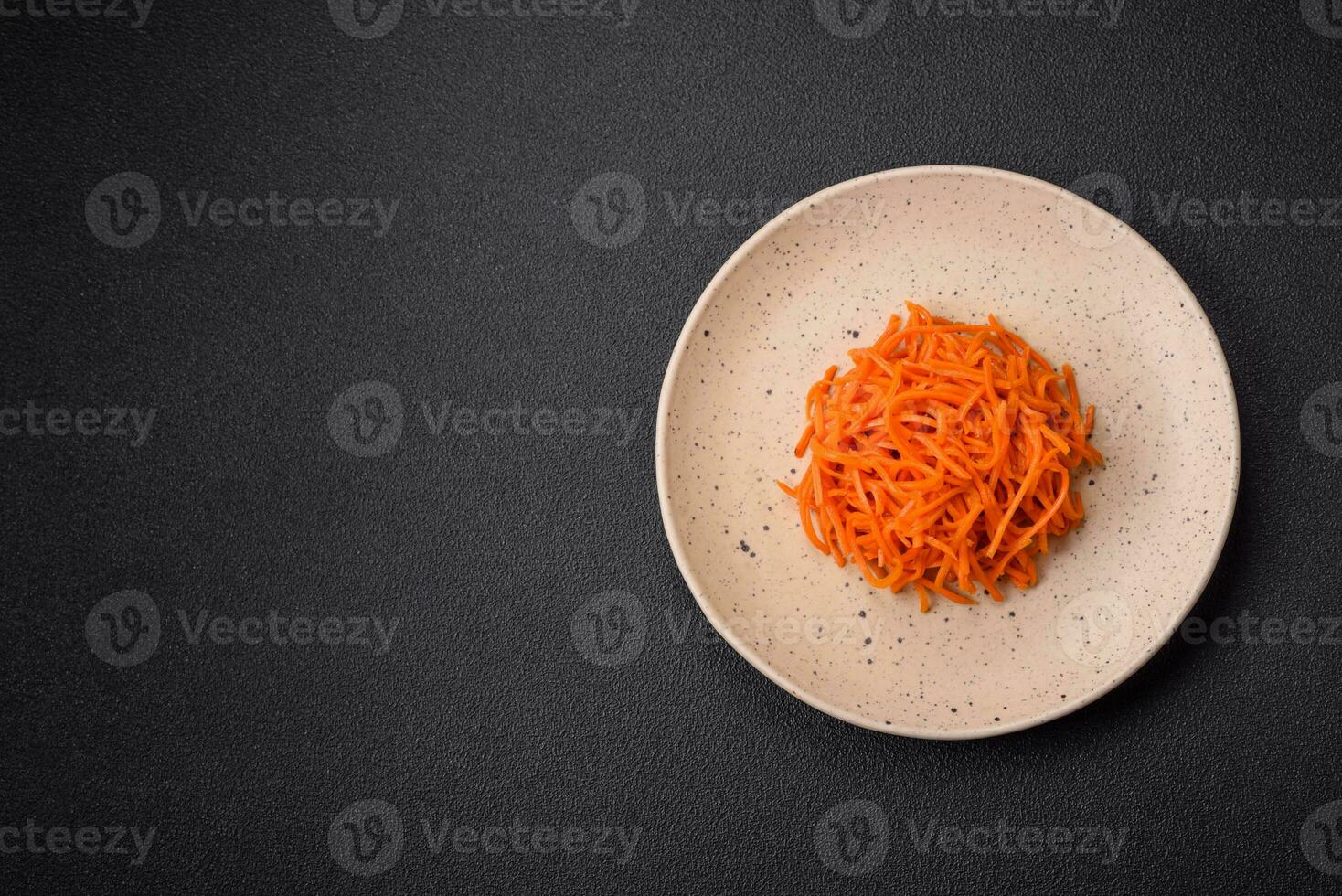 Delicious spicy carrots sliced and cooked in Korean style on a ceramic plate photo