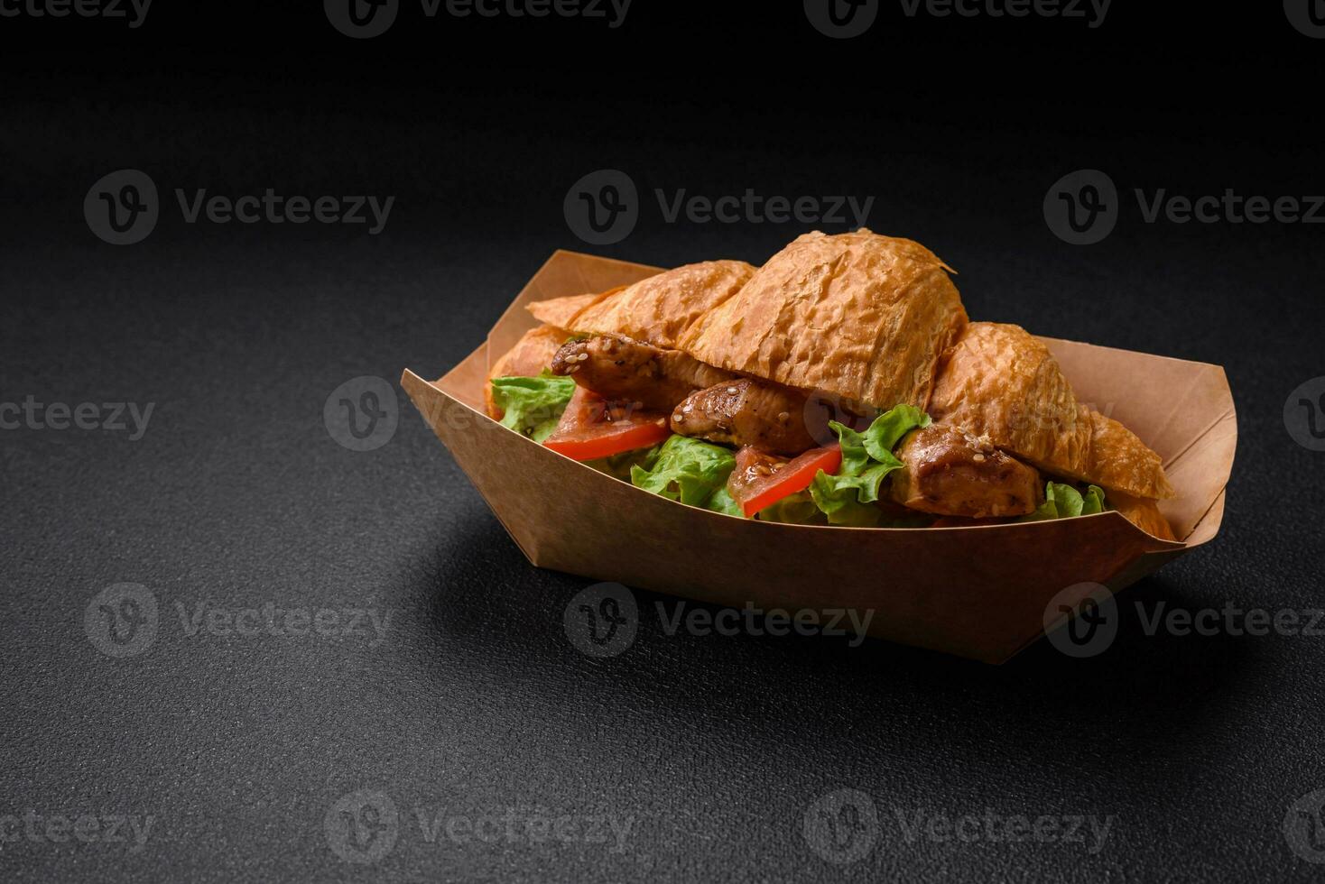 Delicious fresh crispy croissant with chicken or beef meat, lettuce, tomatoes, spices and sauce photo