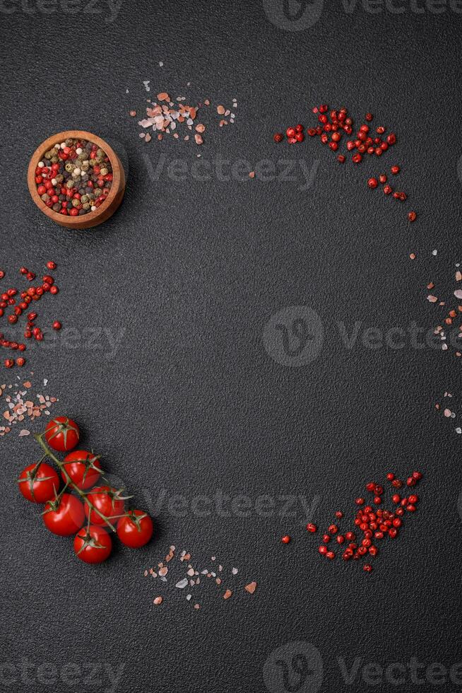 Ingredients salt, spices, herbs and tomatoes on a dark concrete background photo