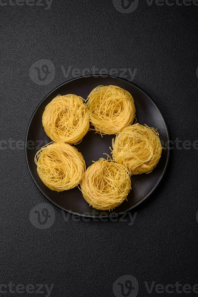 Raw capellini pasta or noodles with salt and spices photo