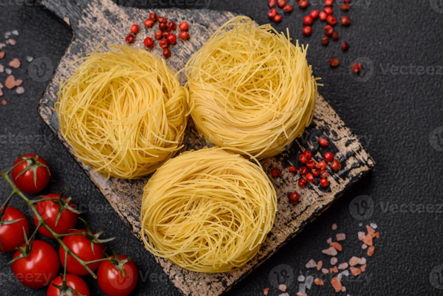 Raw capellini pasta or noodles with salt and spices photo