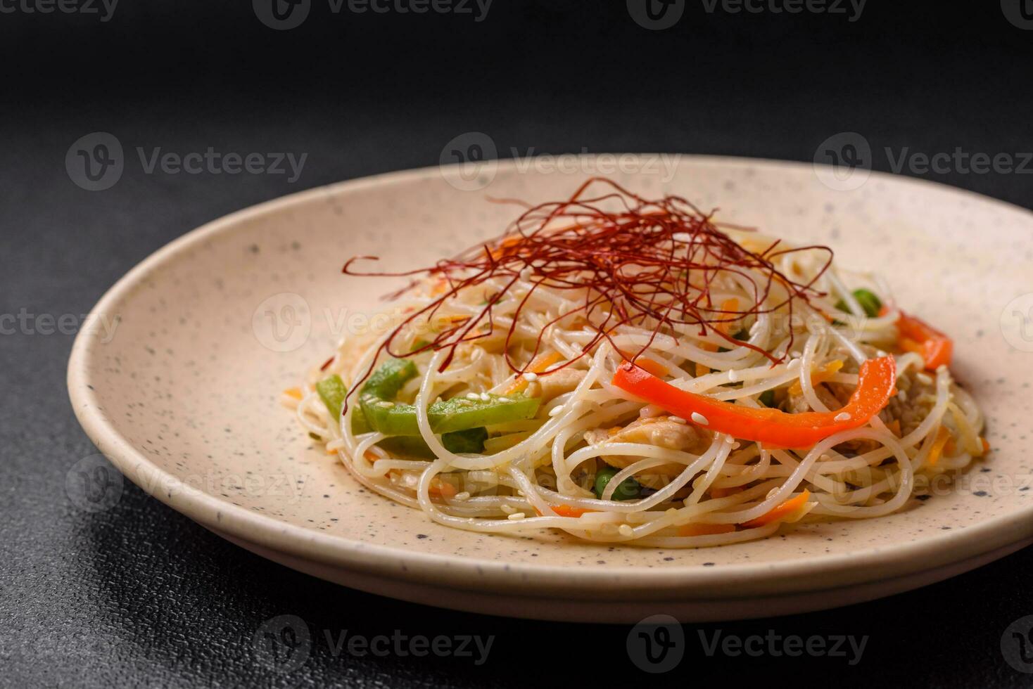sabroso plato de asiático cocina con arroz fideos, pollo, espárragos, pimienta, sésamo semillas foto