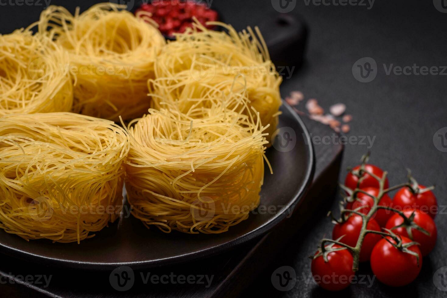 Raw capellini pasta or noodles with salt and spices photo