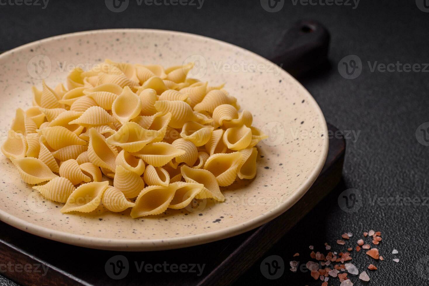 Raw Italian pasta conchiglie from durum wheat with vegetables, salt and spices photo