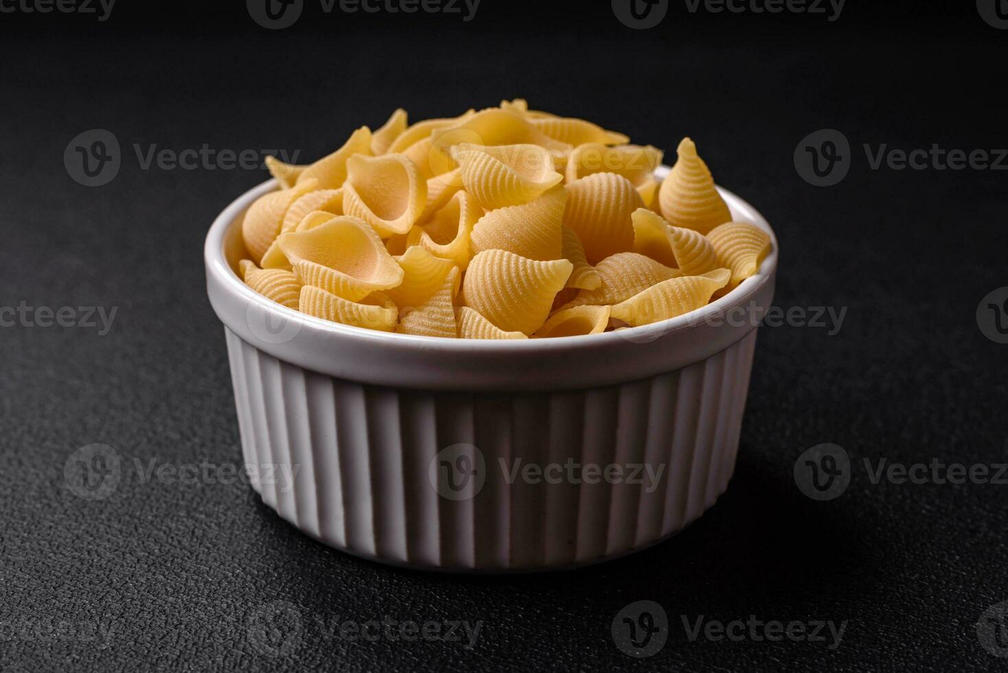 Raw Italian pasta conchiglie from durum wheat with vegetables, salt and spices photo