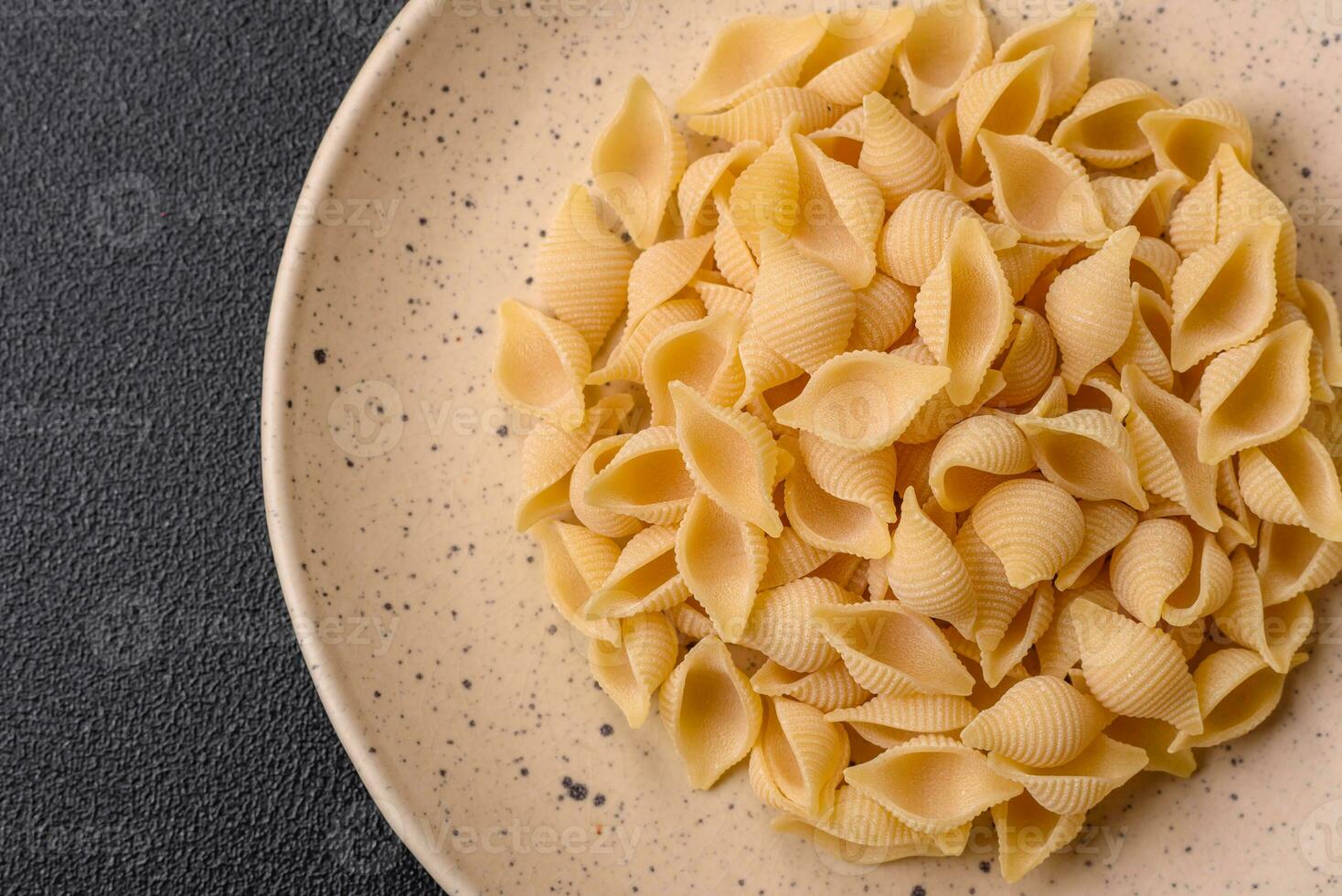 Raw Italian pasta conchiglie from durum wheat with vegetables, salt and spices photo