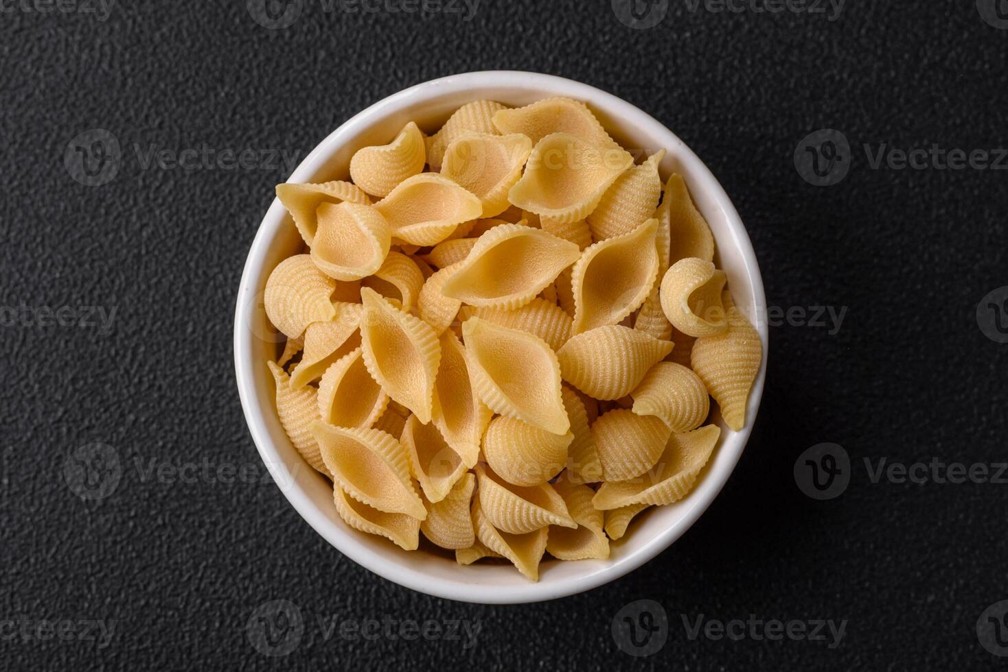 Raw Italian pasta conchiglie from durum wheat with vegetables, salt and spices photo