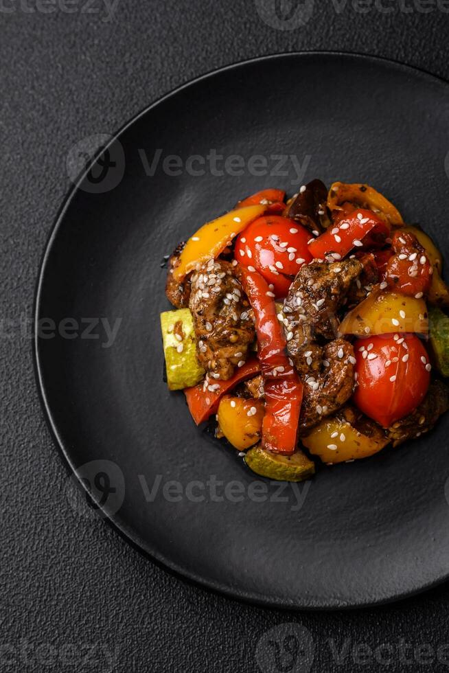 Warm salad with veal, tomatoes, peppers, zucchini, sesame, salt, spices and herbs photo