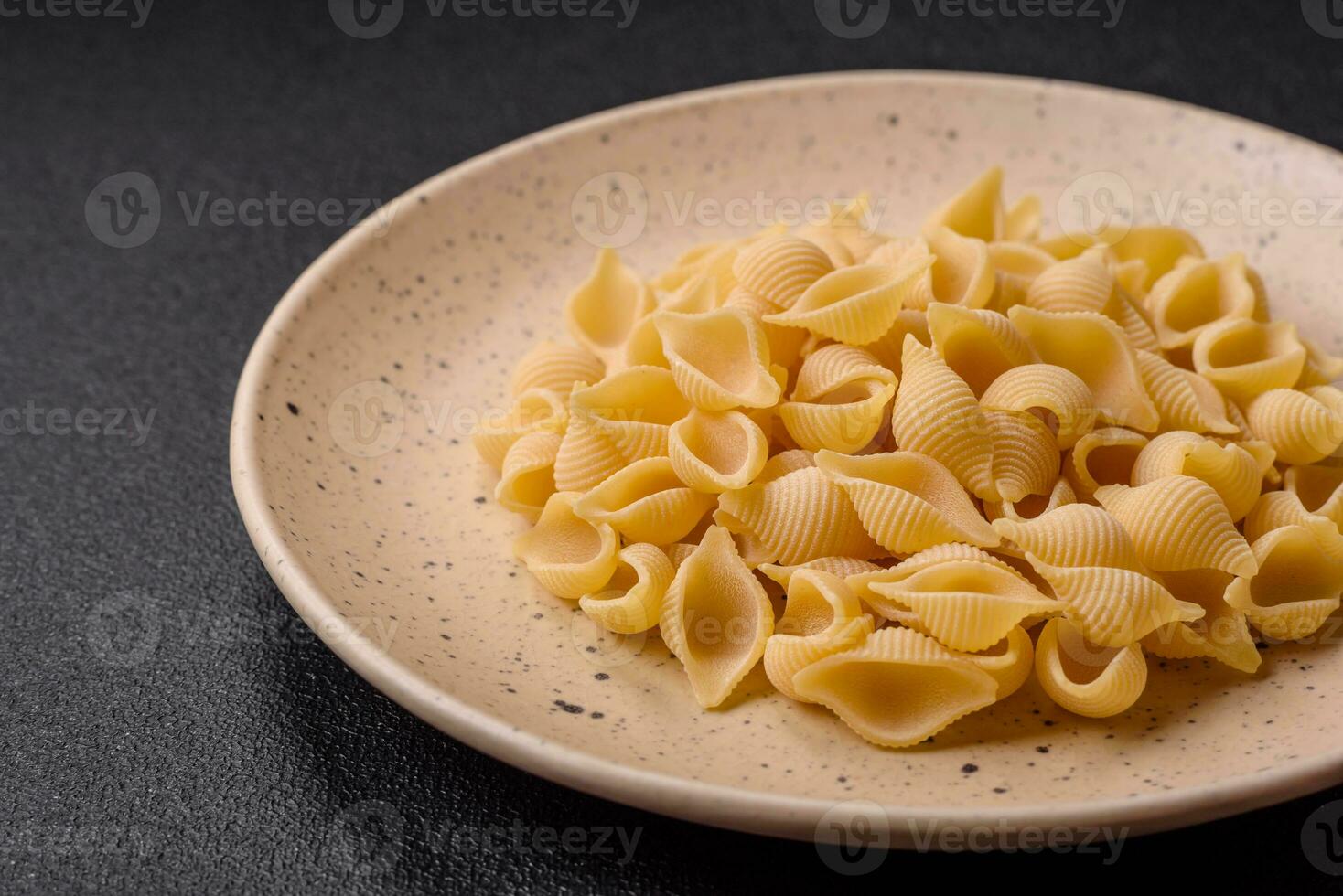 Raw Italian pasta conchiglie from durum wheat with vegetables, salt and spices photo