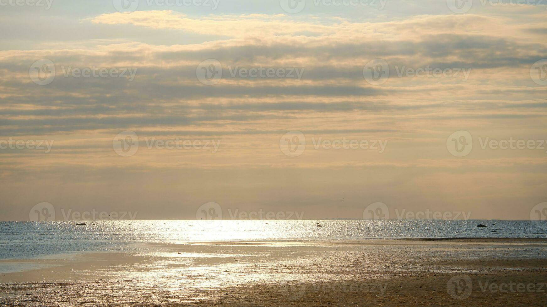 Sunset, illuminated sea. Sandy beach in the foreground. Light waves. Baltic Sea photo