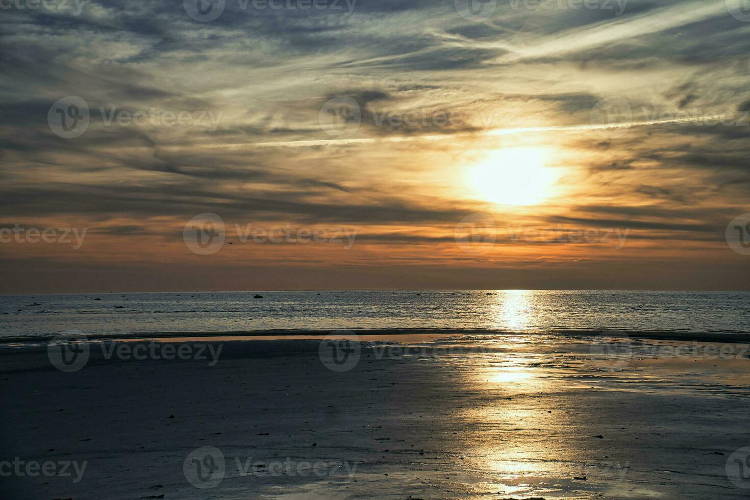 Sunset, illuminated sea. Sandy beach in the foreground. Light waves. Baltic Sea photo