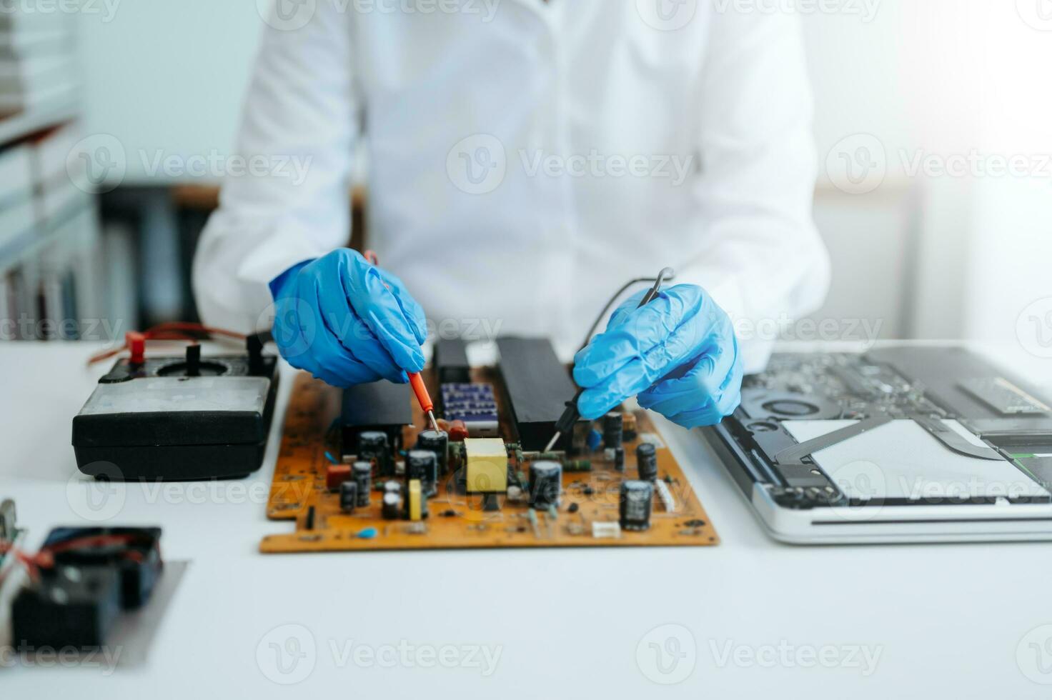 Electronics technician, electronic engineering electronic repair,electronics measuring and testing, repair and maintenance concepts.uses a voltage meter to check and upgrade photo