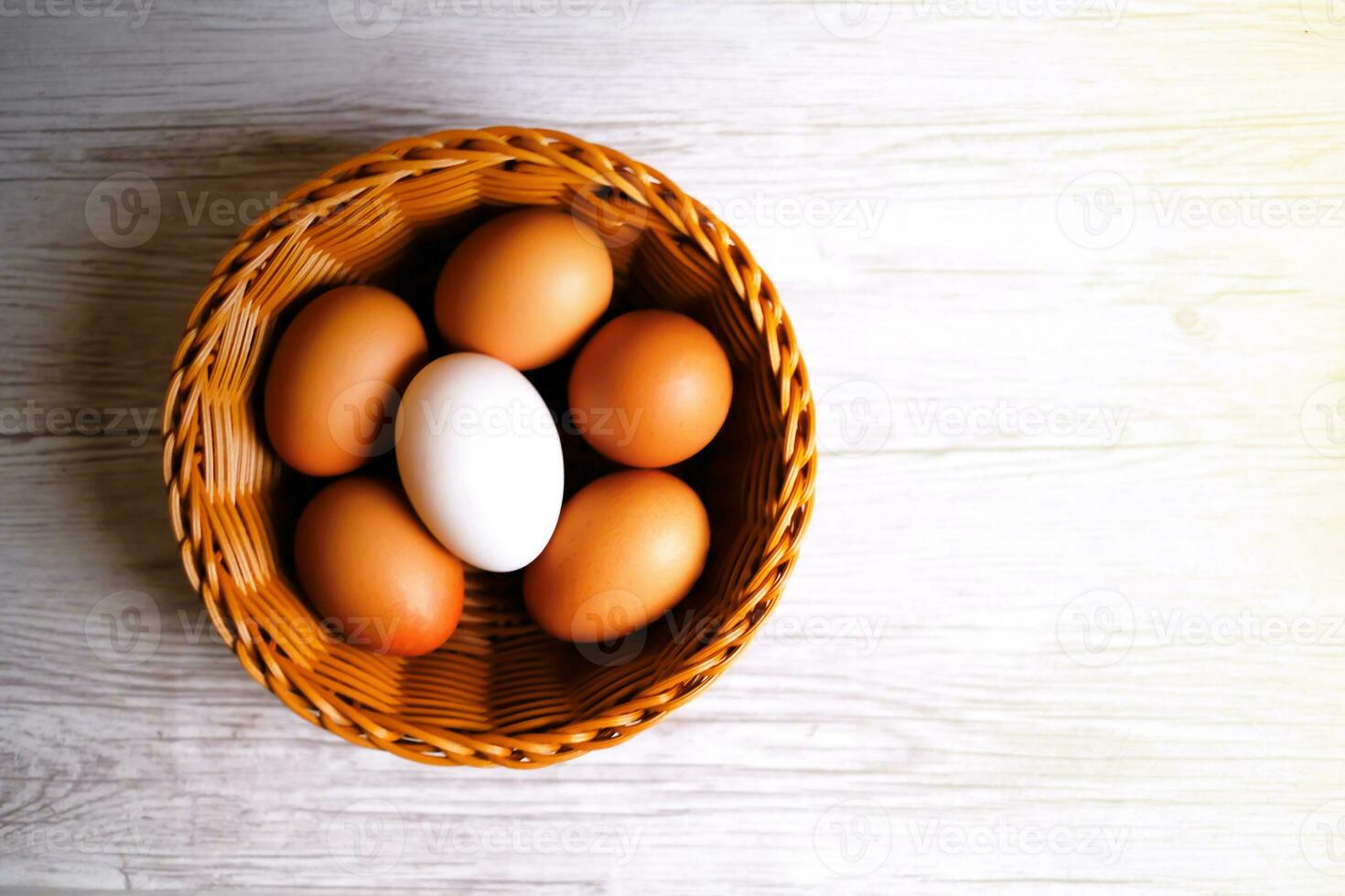 The eggs in the brown wicker basket on the table. photo