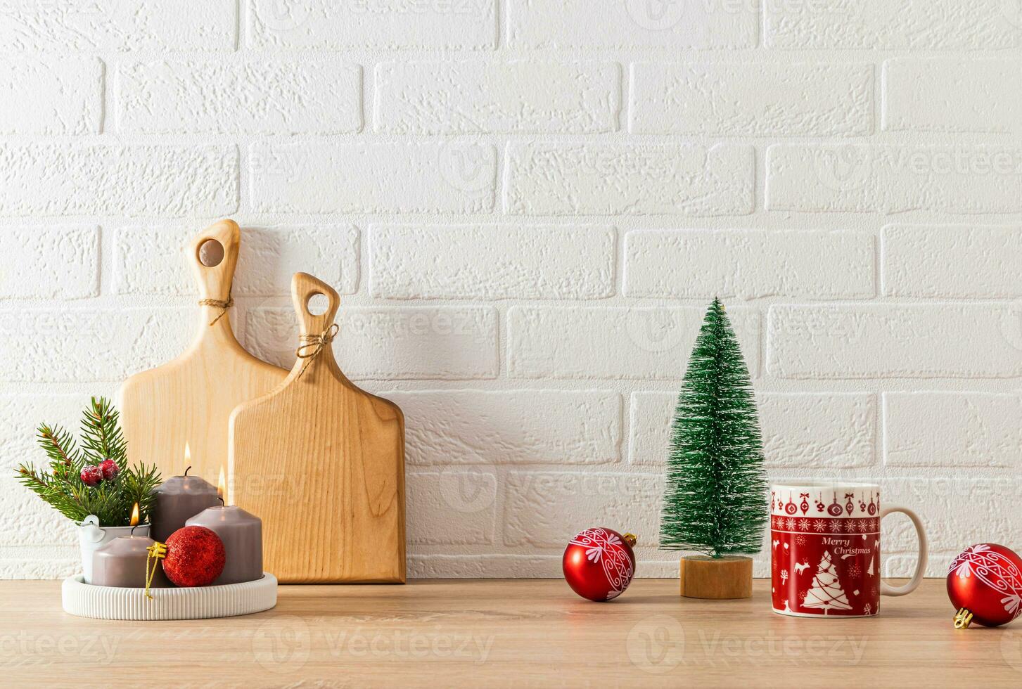 Red mugs with Christmas pattern, candle set, red ball and decorative Christmas tree on kitchen countertop. Festive kitchen background. minimalism. photo