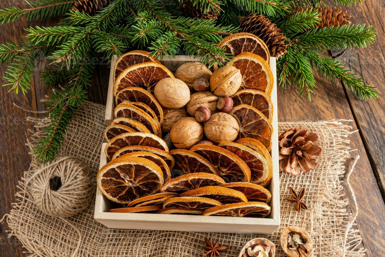 Traditional Christmas decorations of dried orange slices and walnut in a large wooden box on a rustic table. Natural eco-style holiday. photo