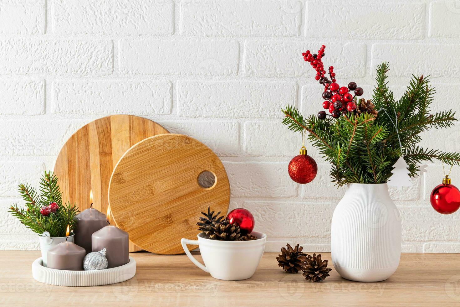 a fragment of a white wooden countertop with various kitchen utensils and Christmas decorations. candles, balls, branches of spruce. photo