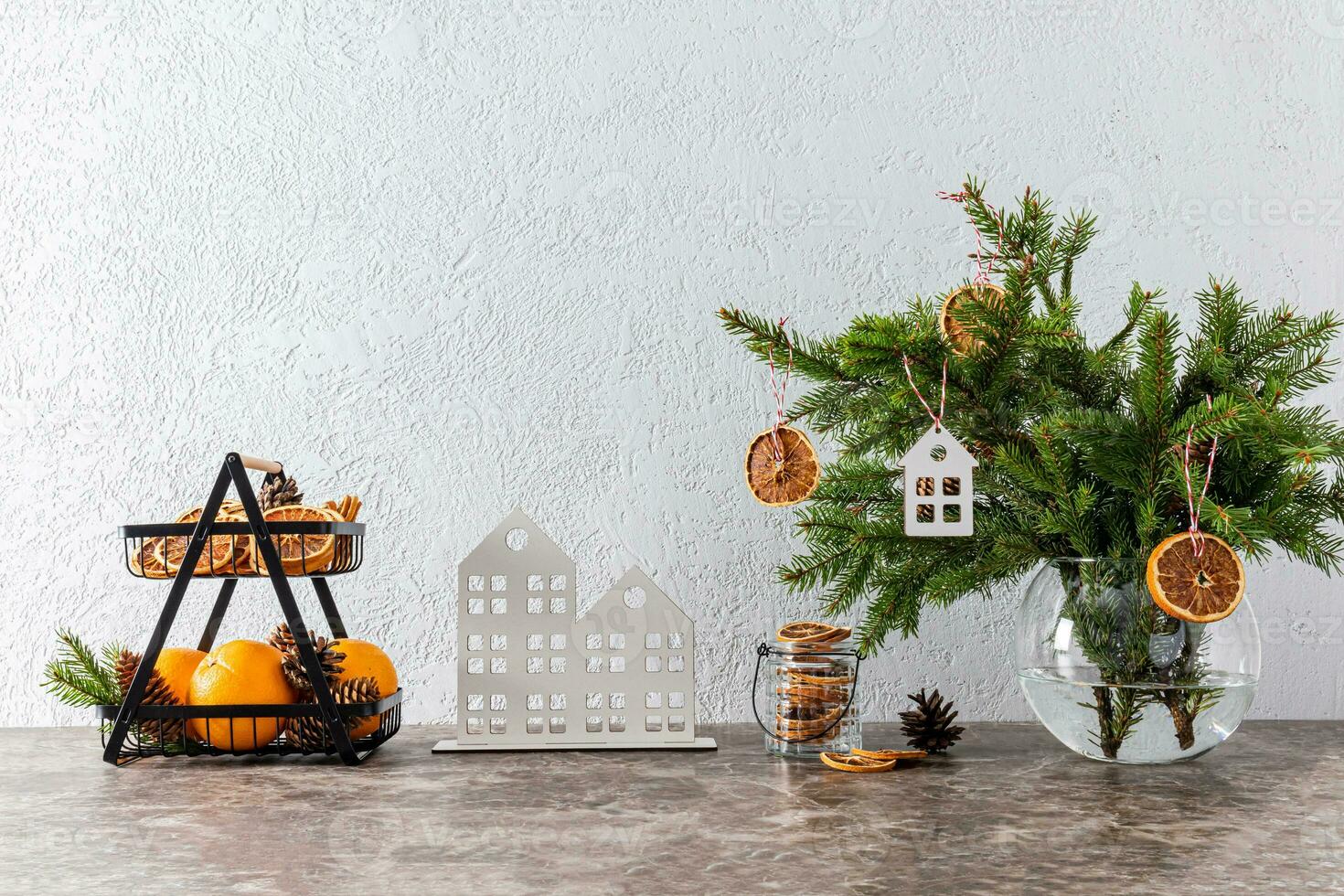 Spruce branches in a white jug decorated with dry orange slices and a stylish basket of fresh oranges fruits on the New Year's countertop photo