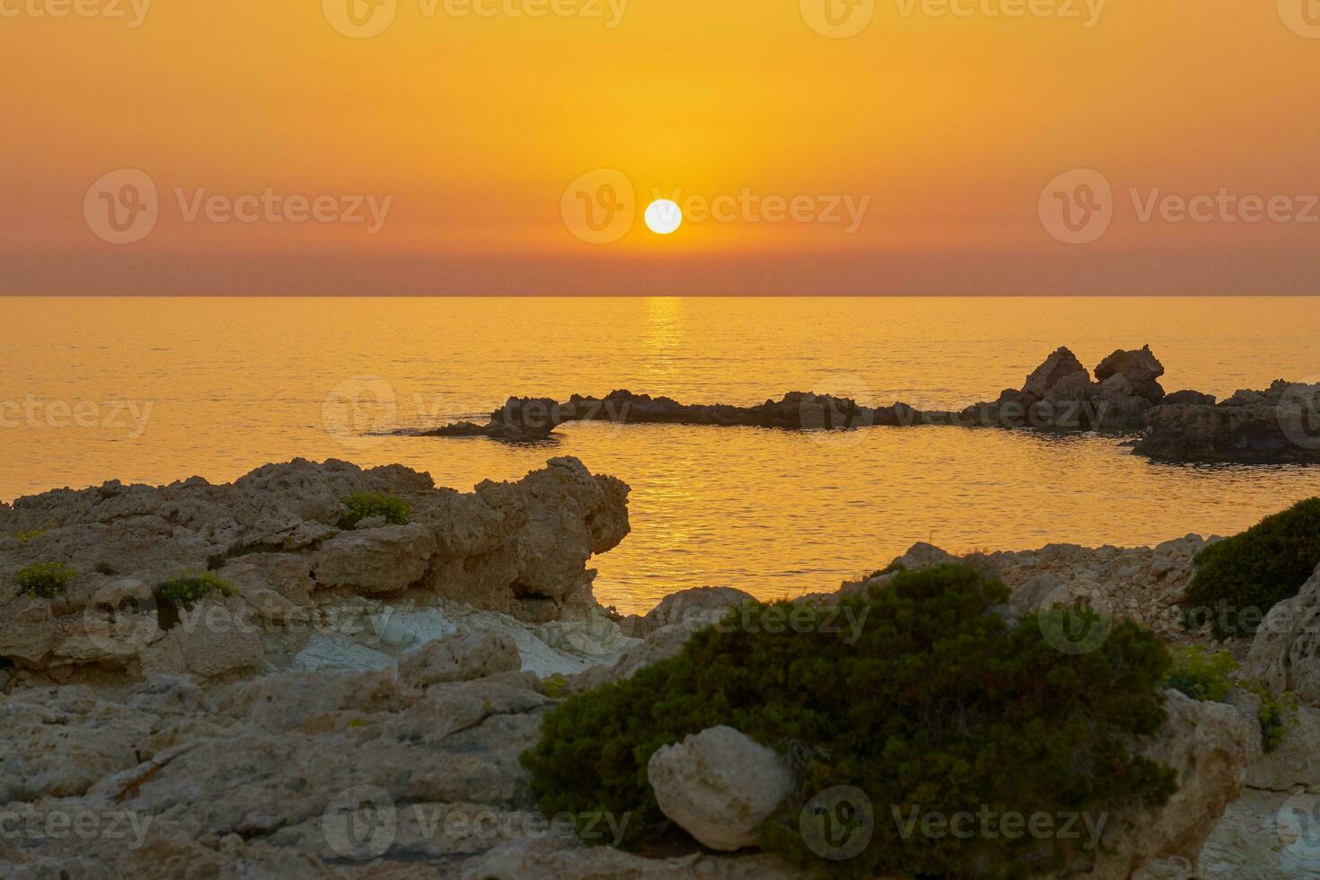 The stone coast of the Mediterranean Sea at sunset. photo