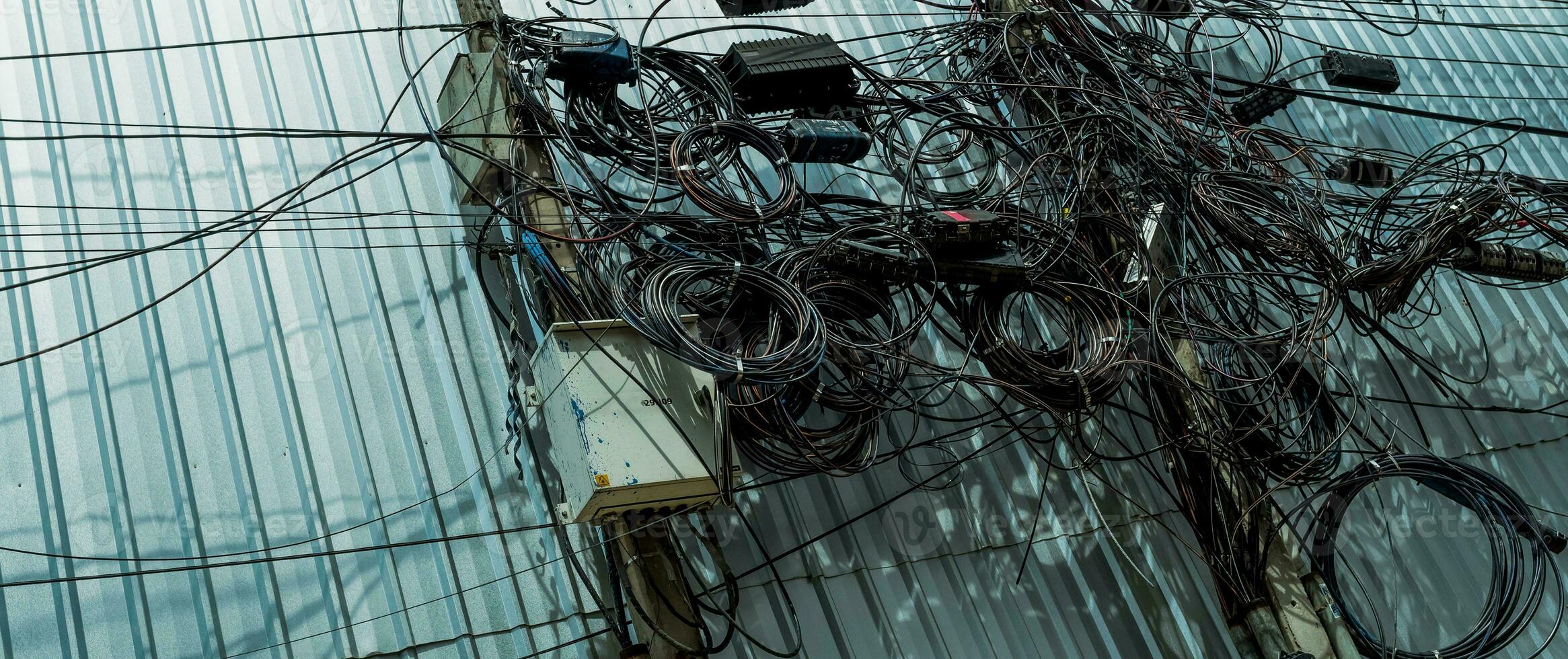 Tangled electrical wires and tangled communication lines on urban electric poles create a chaotic network. Disorganized and messy to organization management concept. Should take underground wire. photo
