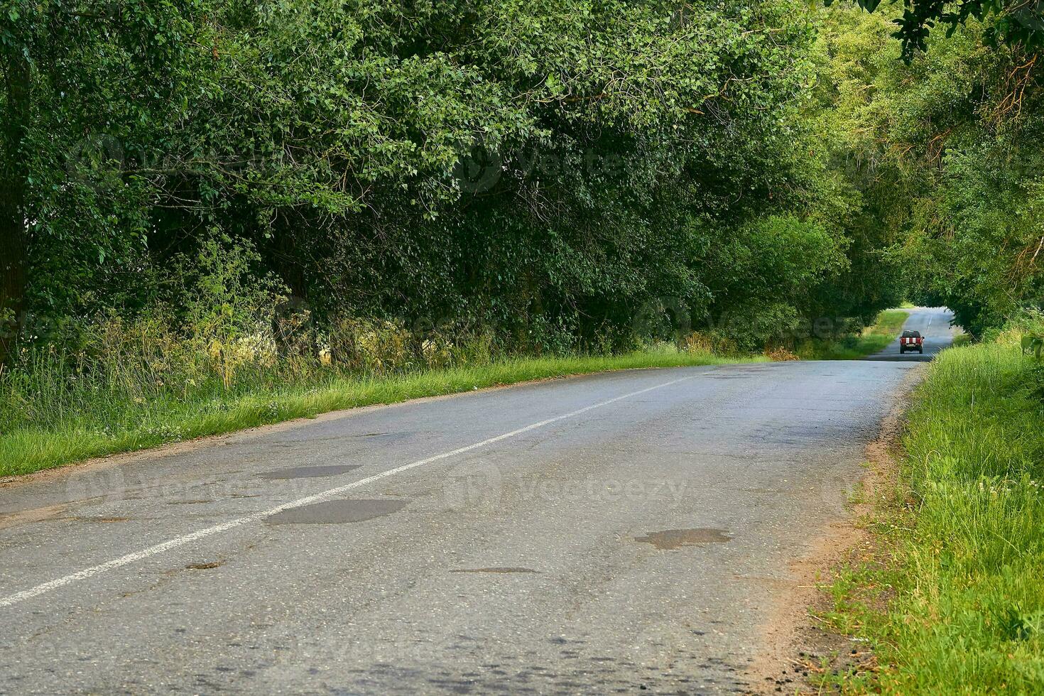 Travelling by car. Asphalt road among summer fields of green plantings photo