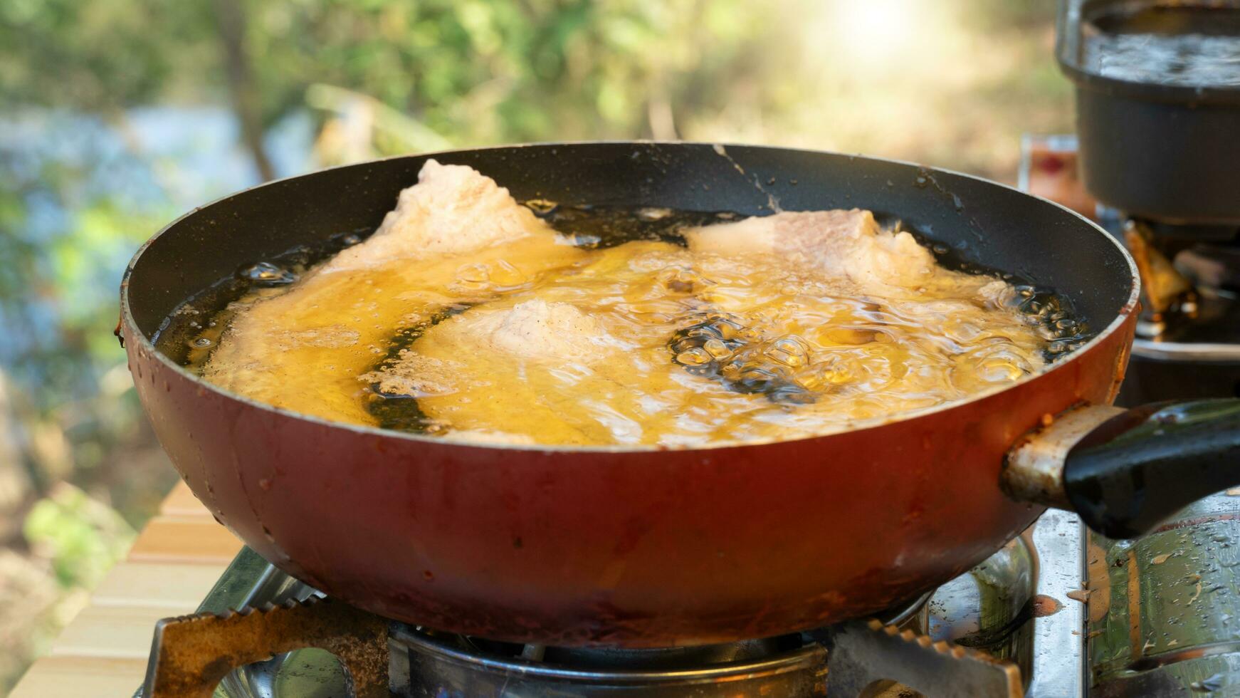 Abstract of Oil to cover the pork used for frying. In a pan, the inside is black and the outside is red. Cooking a picnic outside. photo