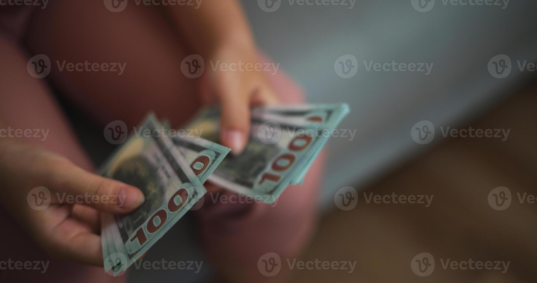 Portrait close up hands of young Asian woman enjoy counting cash dollars banknotes on sofa in the living room at home. photo