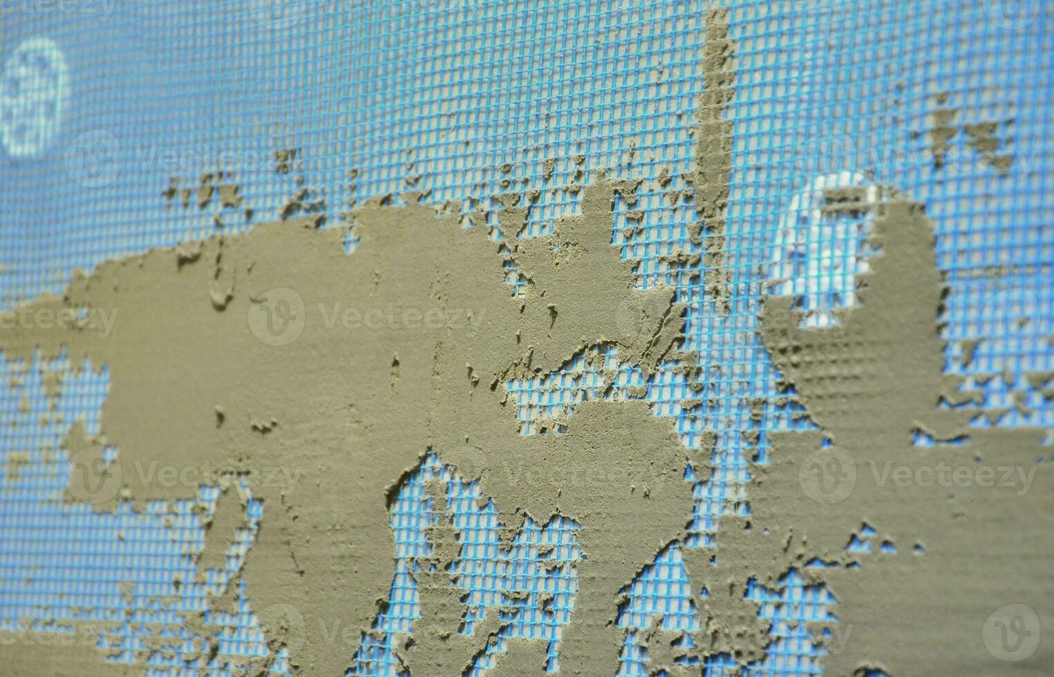 The texture of the wall, covered with gray foam polystyrene plates, covered with a blue reinforcing mesh and covered with a mixture for gluing it. Stage of wall insulation photo