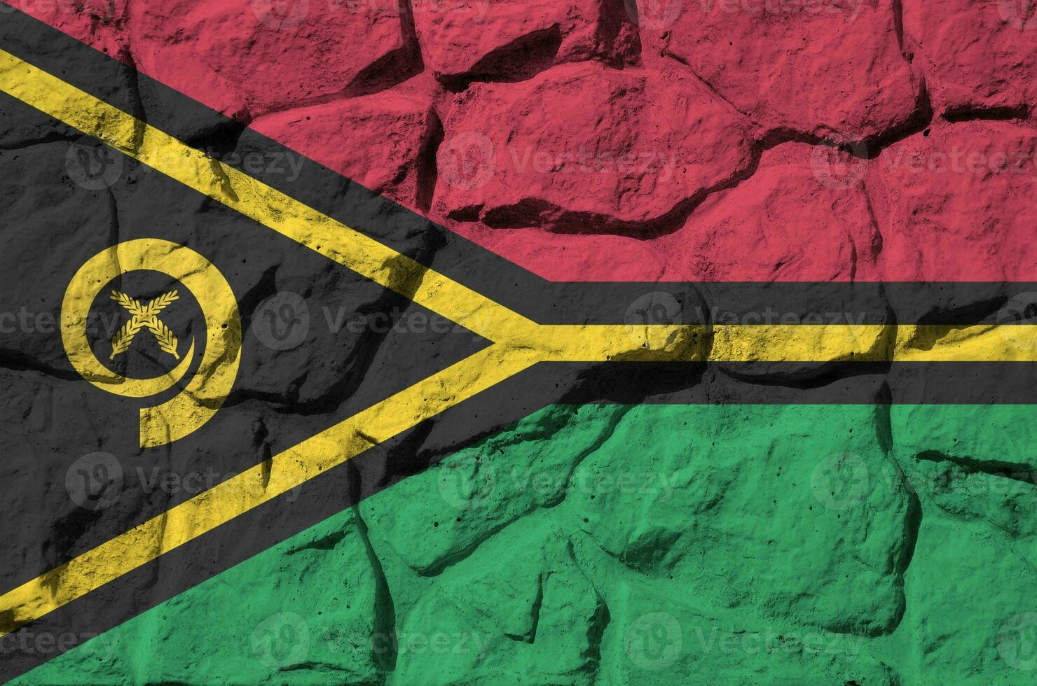 Vanuatu flag depicted in paint colors on old stone wall closeup. Textured banner on rock wall background photo