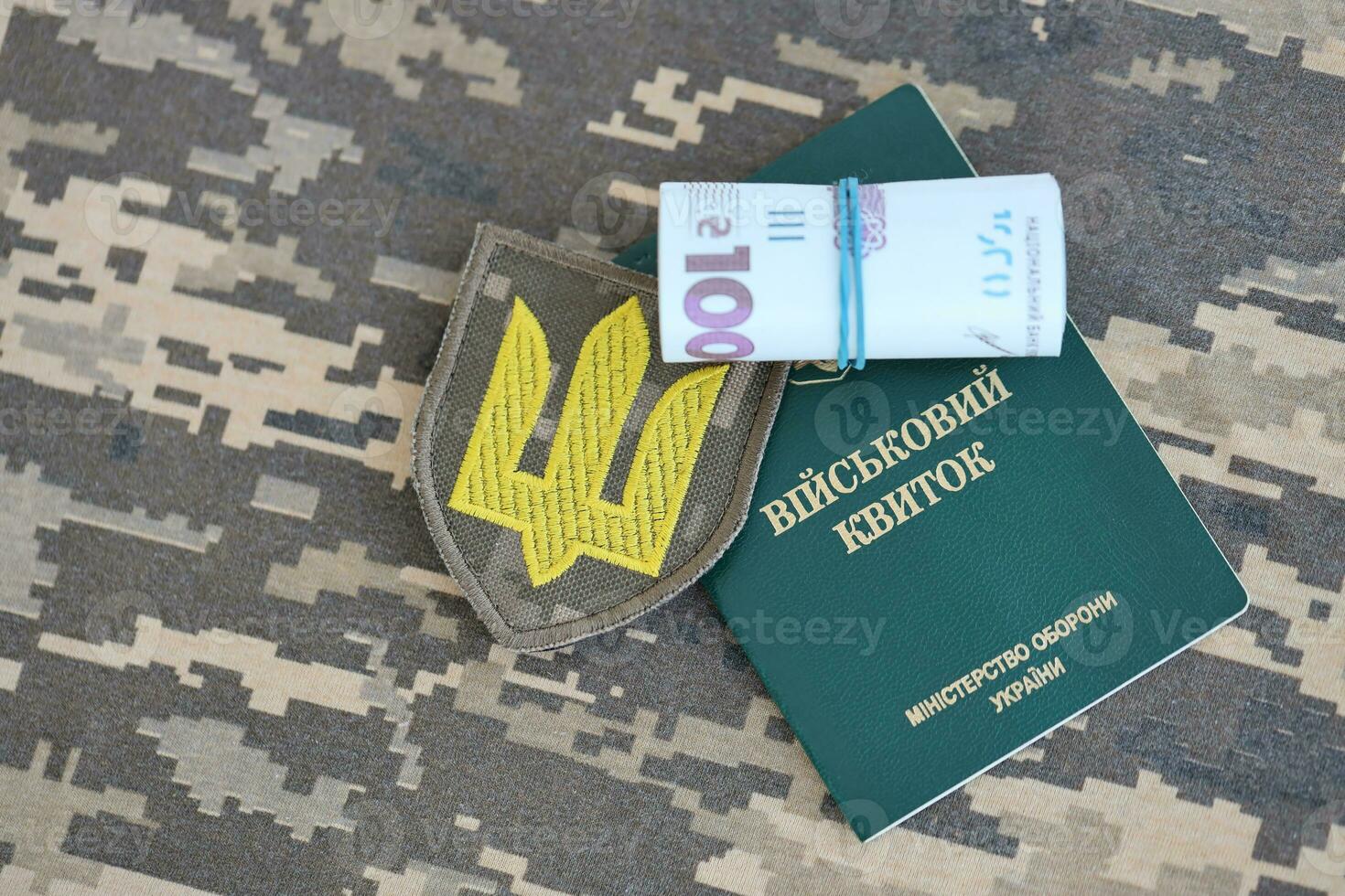 Symbol of Ukrainian army and military ID with bunch of money on the camouflage uniform of a Ukrainian soldier. Concept of payment to military personnel or bribe for deferment from service photo