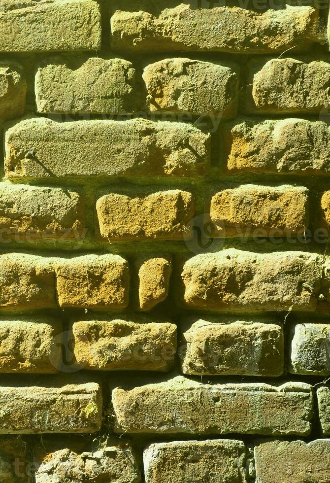 Vertical wall texture of several rows of very old brickwork made of red brick. Shattered and damaged brick wall with pinched corners photo