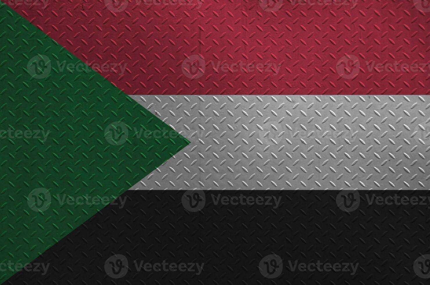 Sudan flag depicted in paint colors on old brushed metal plate or wall closeup. Textured banner on rough background photo