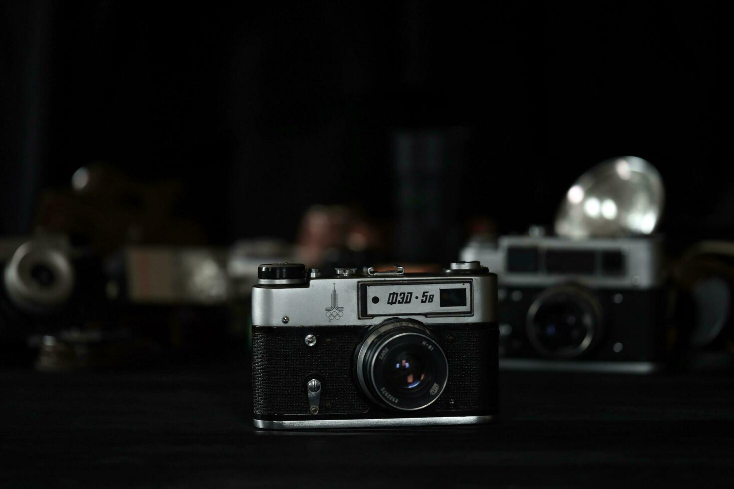 KHARKOV, UKRAINE - APRIL 27, 2021 Fed 4 and 5b Film photo camera and another old retro photo equipment on black wooden table in photographer darkroom. Photographic gear from soviet union