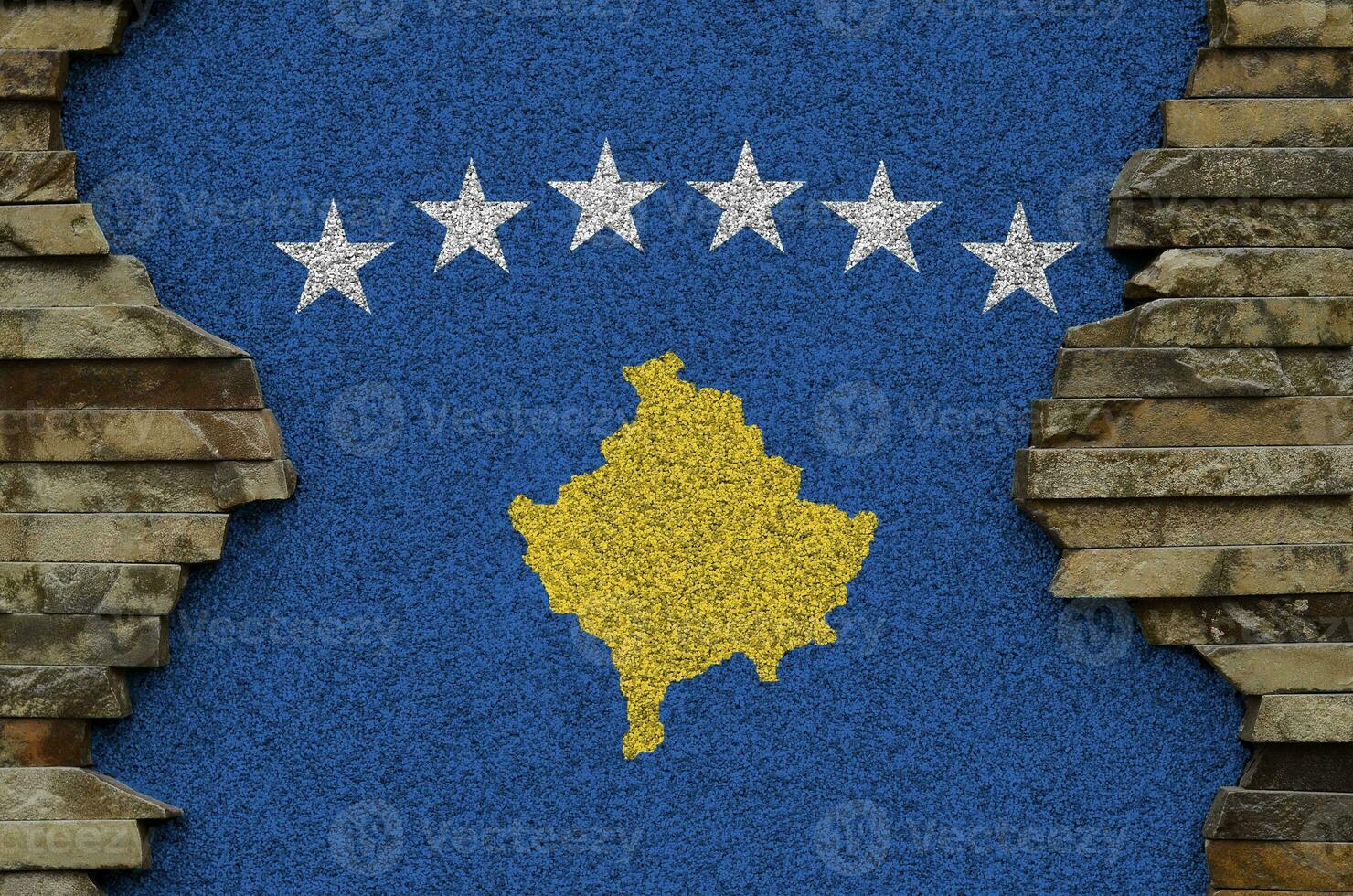 Kosovo flag depicted in paint colors on old stone wall closeup. Textured banner on rock wall background photo