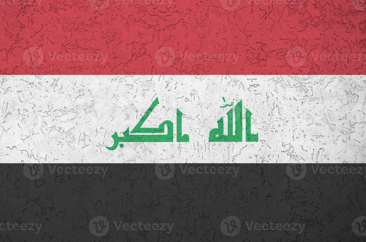 Iraq flag depicted in bright paint colors on old relief plastering wall. Textured banner on rough background photo