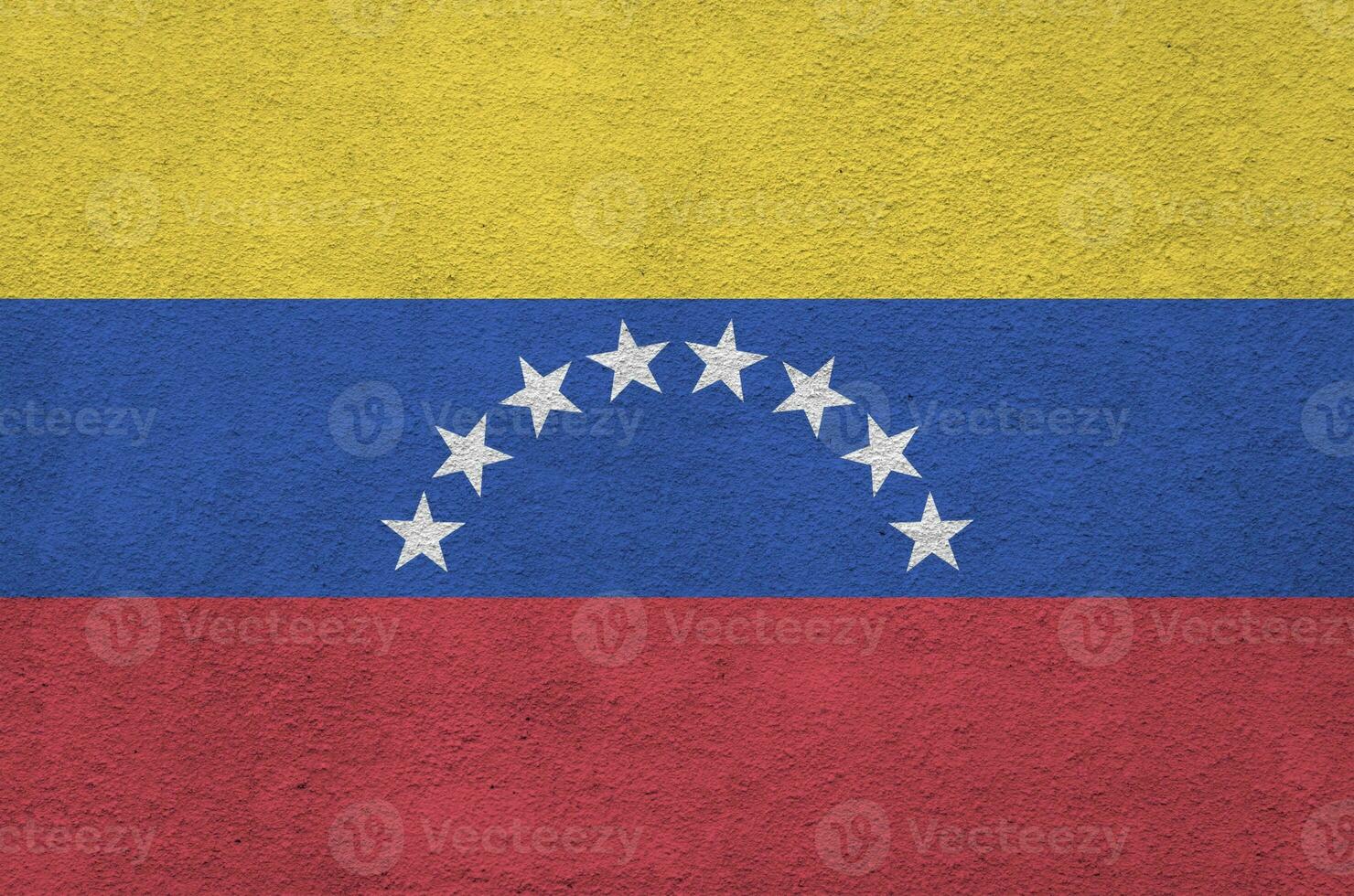 Venezuela flag depicted in bright paint colors on old relief plastering wall. Textured banner on rough background photo