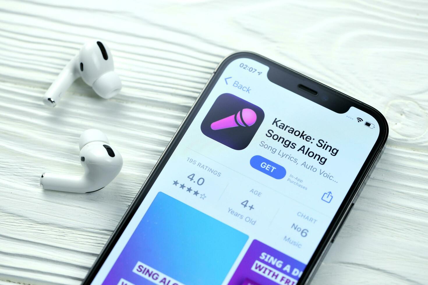 KHARKOV, UKRAINE - MARCH 5, 2021 Karaoke icon and application from App store on iPhone 12 pro display screen with airpods pro on white table photo