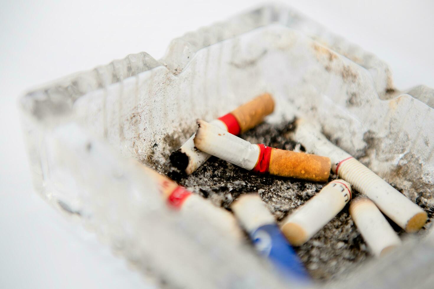 Close-up of cigarette butt in ashtray. Glass cigarette ashtray on white background. Concept of health and dangers of smoking. photo