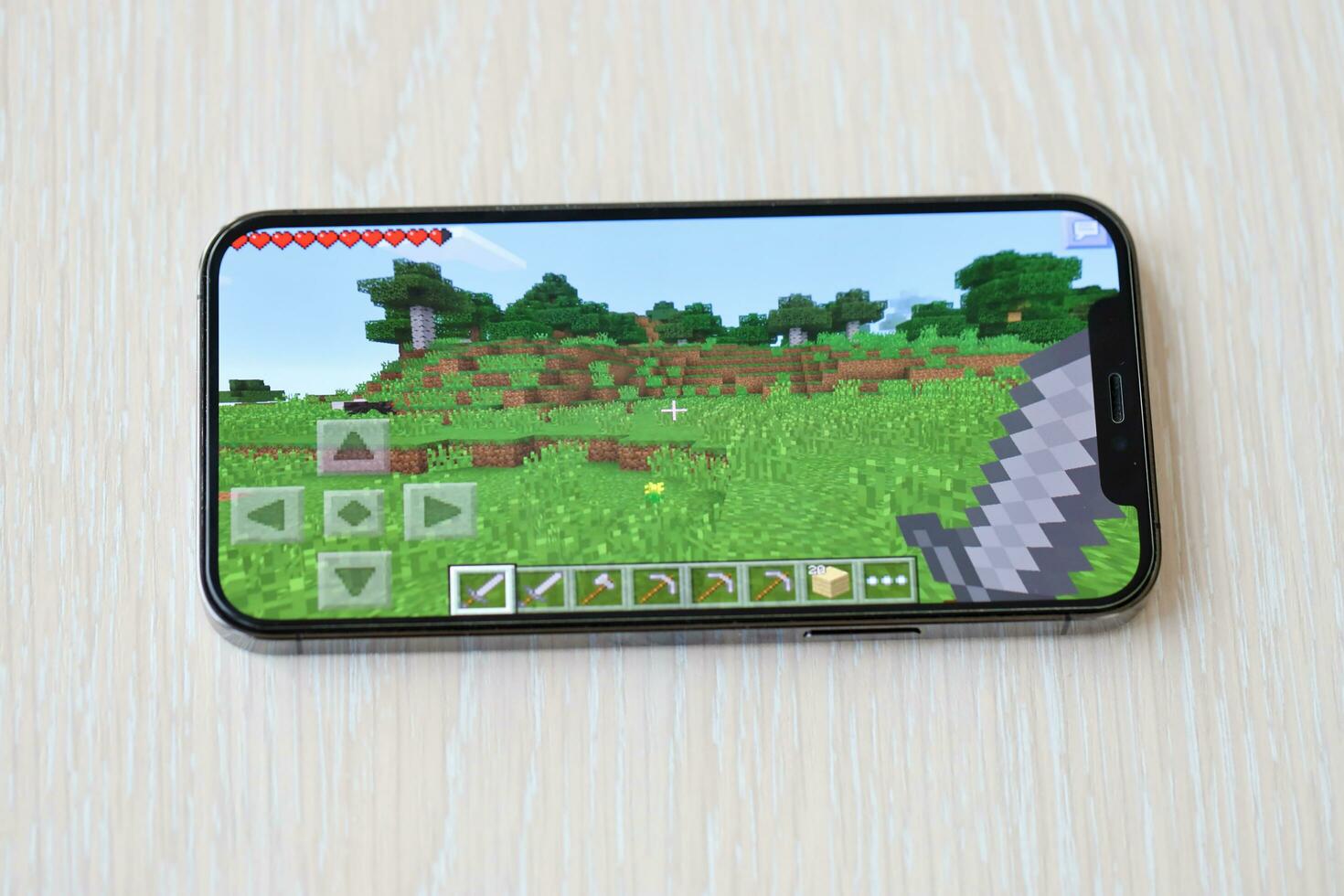 Minecraft mobile iOS game on iPhone 15 smartphone screen on wooden table during mobile gameplay photo